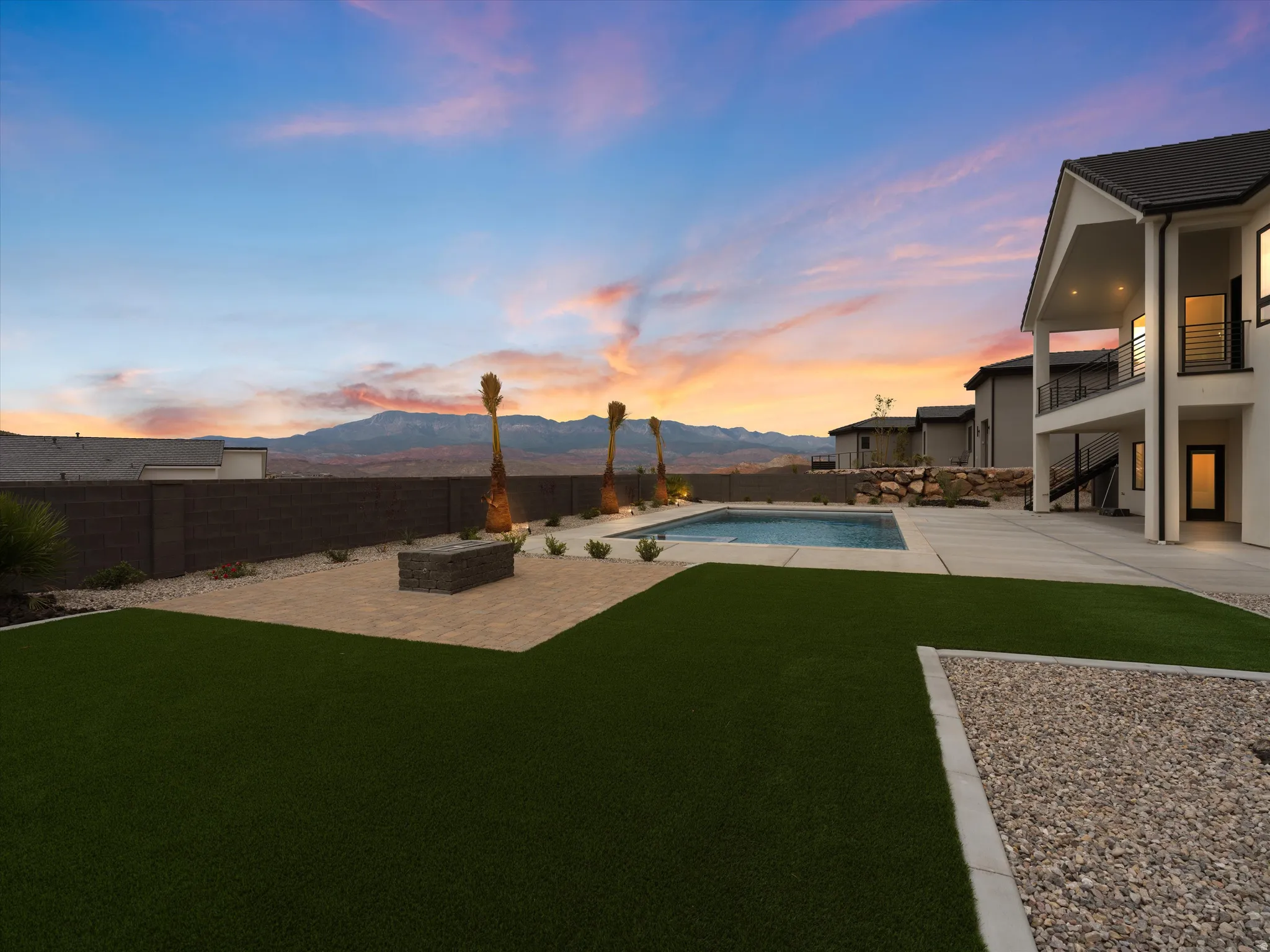 Expansive backyard featuring artificial turf, a rectangular swimming pool, and a large concrete patio