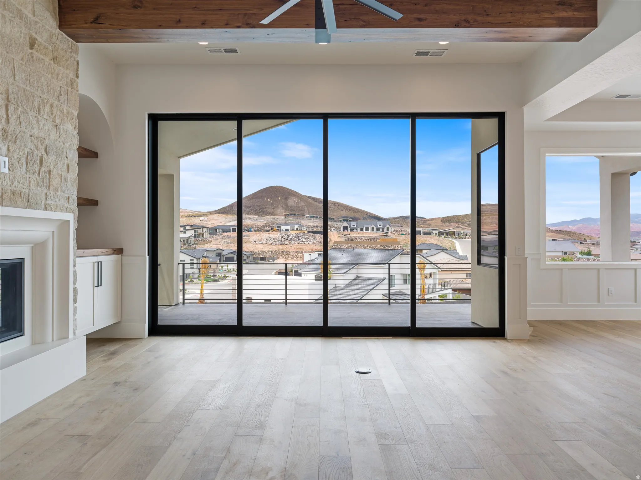 Expansive sliding glass doors opening to a balcony with mountain scenery