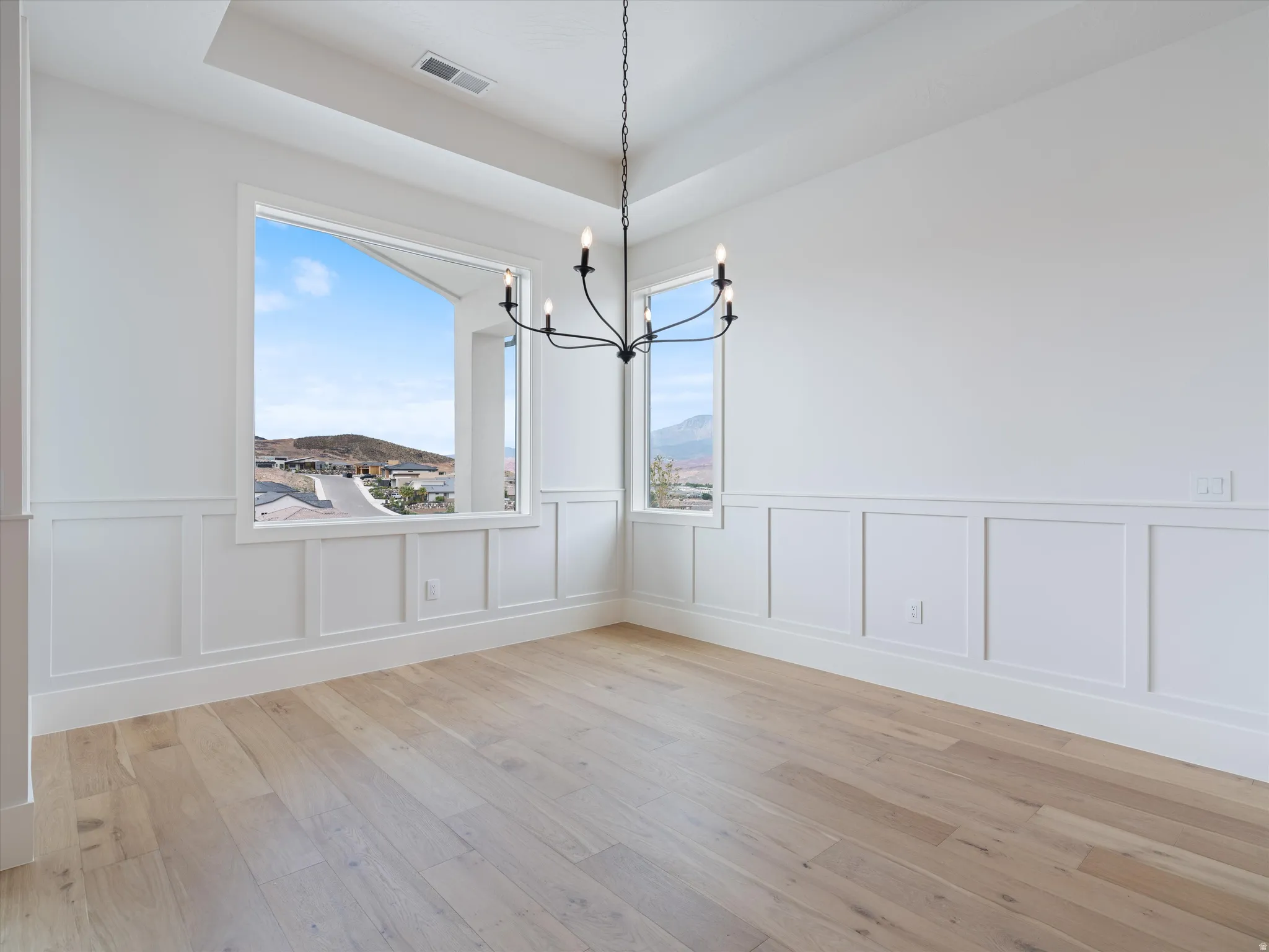 Bright interior room featuring a tray ceiling, a large picture window, and board and batten wall detailing