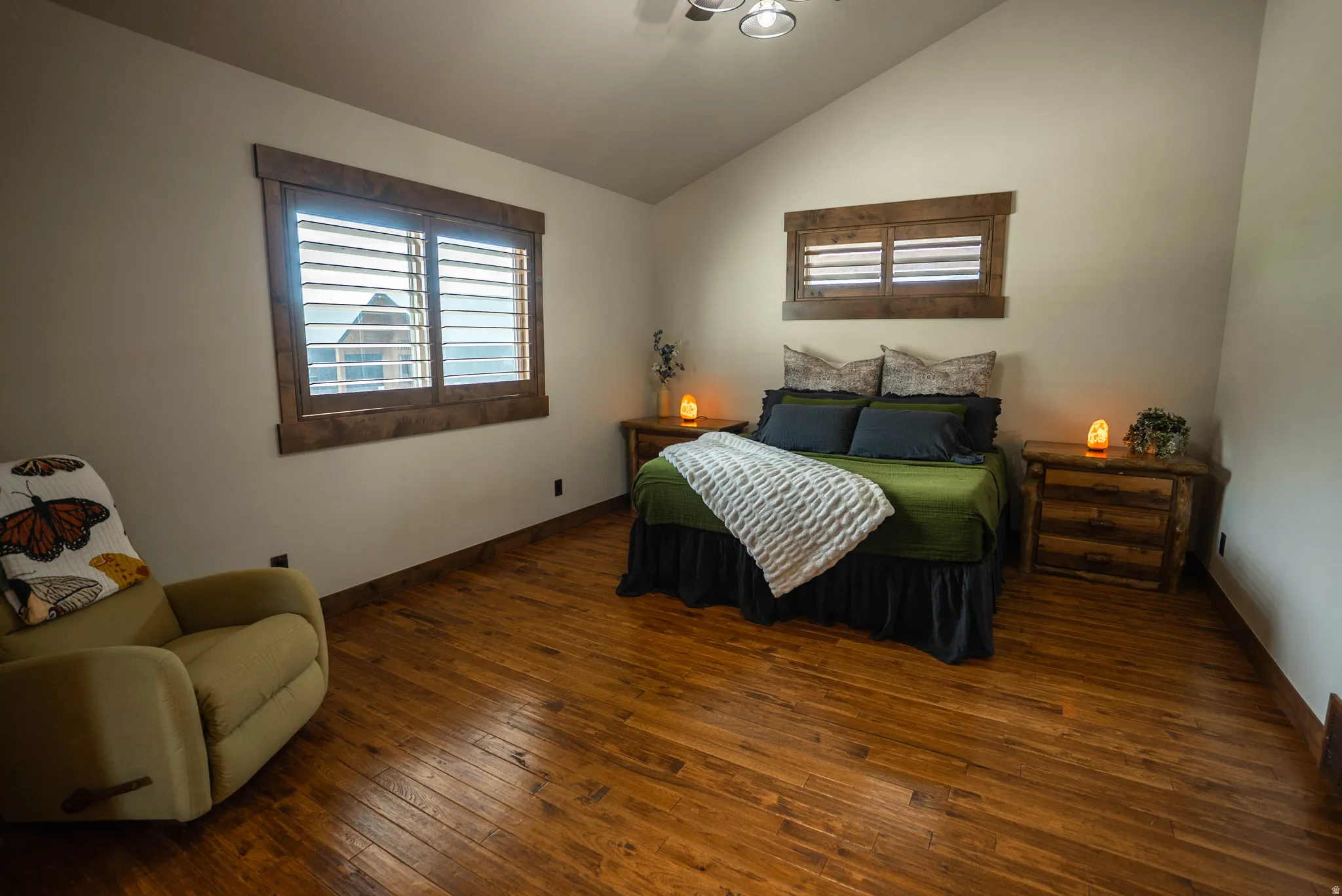 Vaulted ceilings crown this space featuring wood-finish flooring and solid wood window trim with plantation shutters