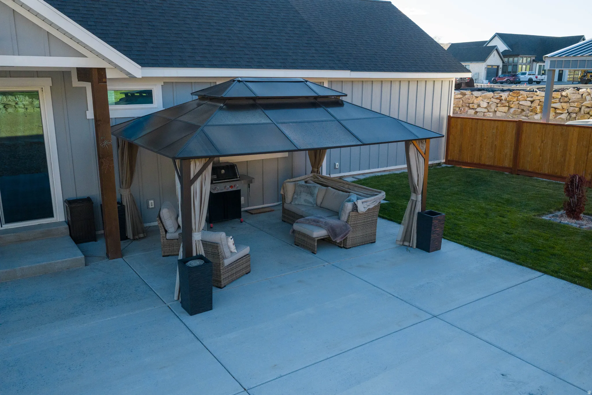 Spacious concrete patio featuring a gazebo with a metal roof and side curtains