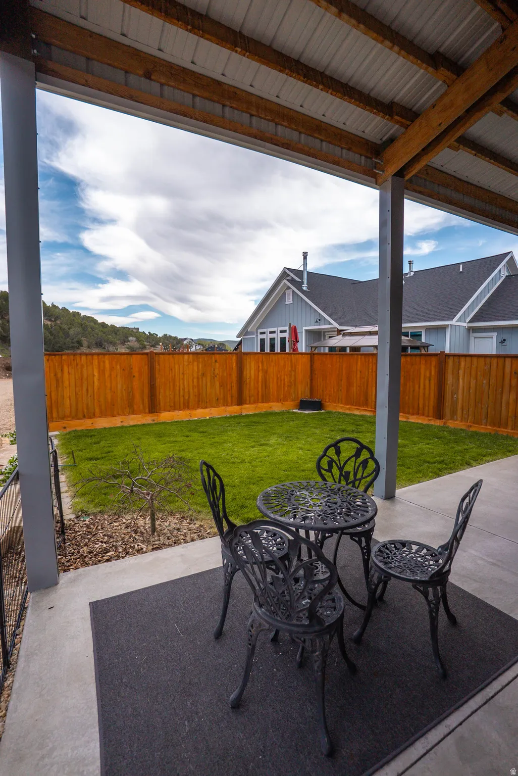 Covered patio with concrete flooring, wood beam accents, and a corrugated metal ceiling