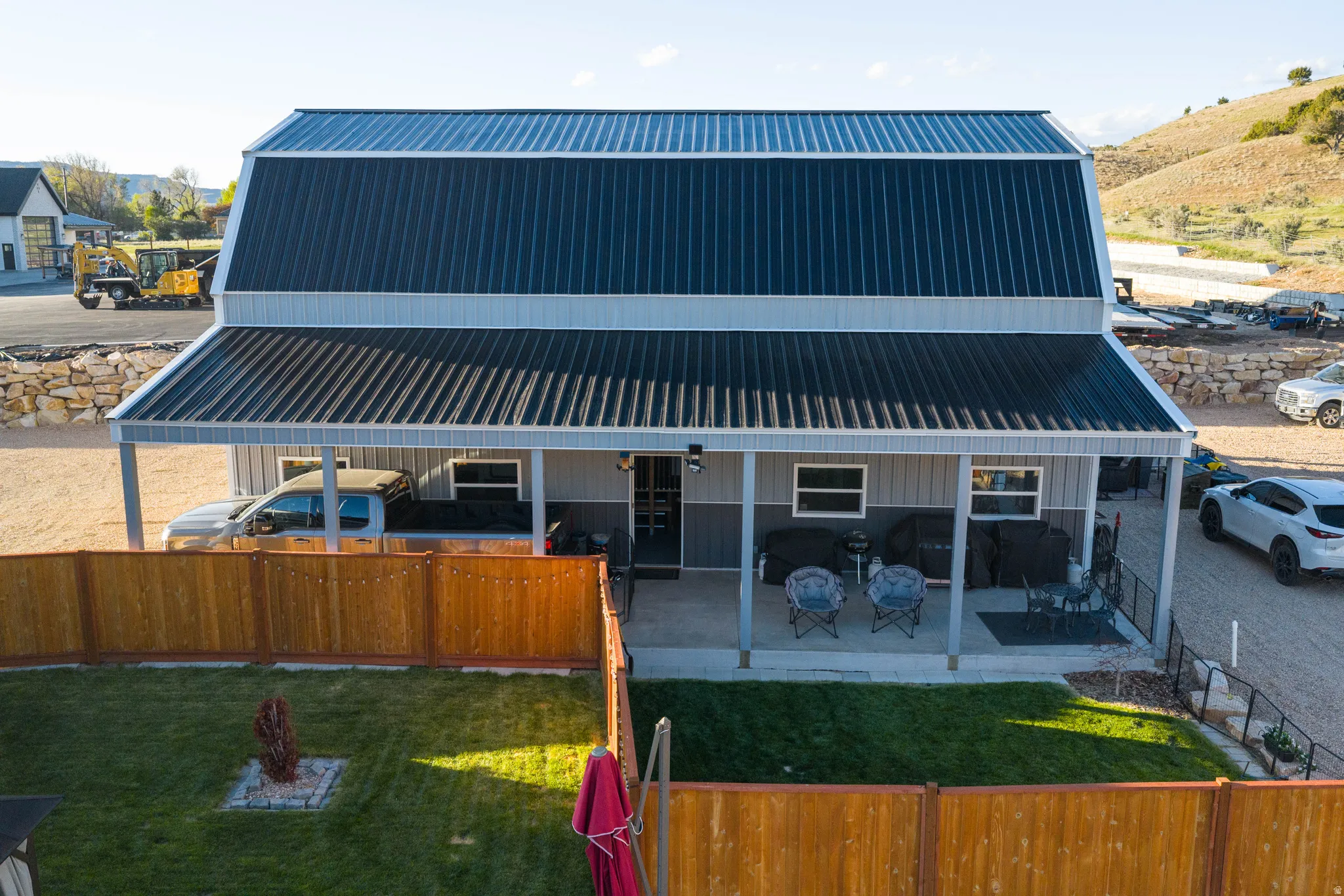 Barn-style structure featuring a black metal gambrel roof and light gray siding
