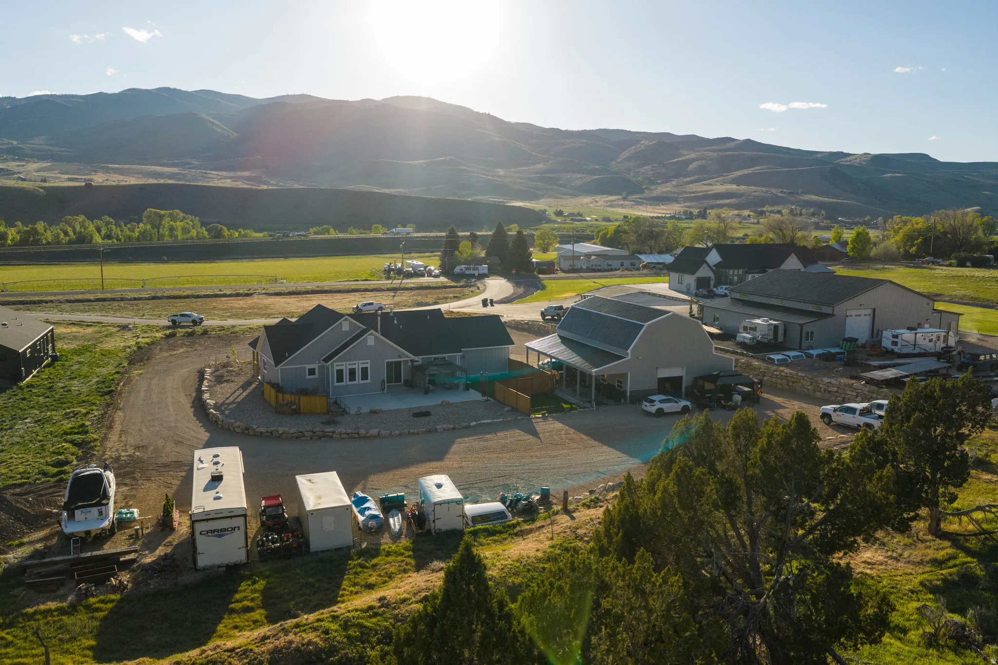 Expansive property featuring a contemporary residence, a large barn-style building with a covered patio, and a substantial industrial-style building