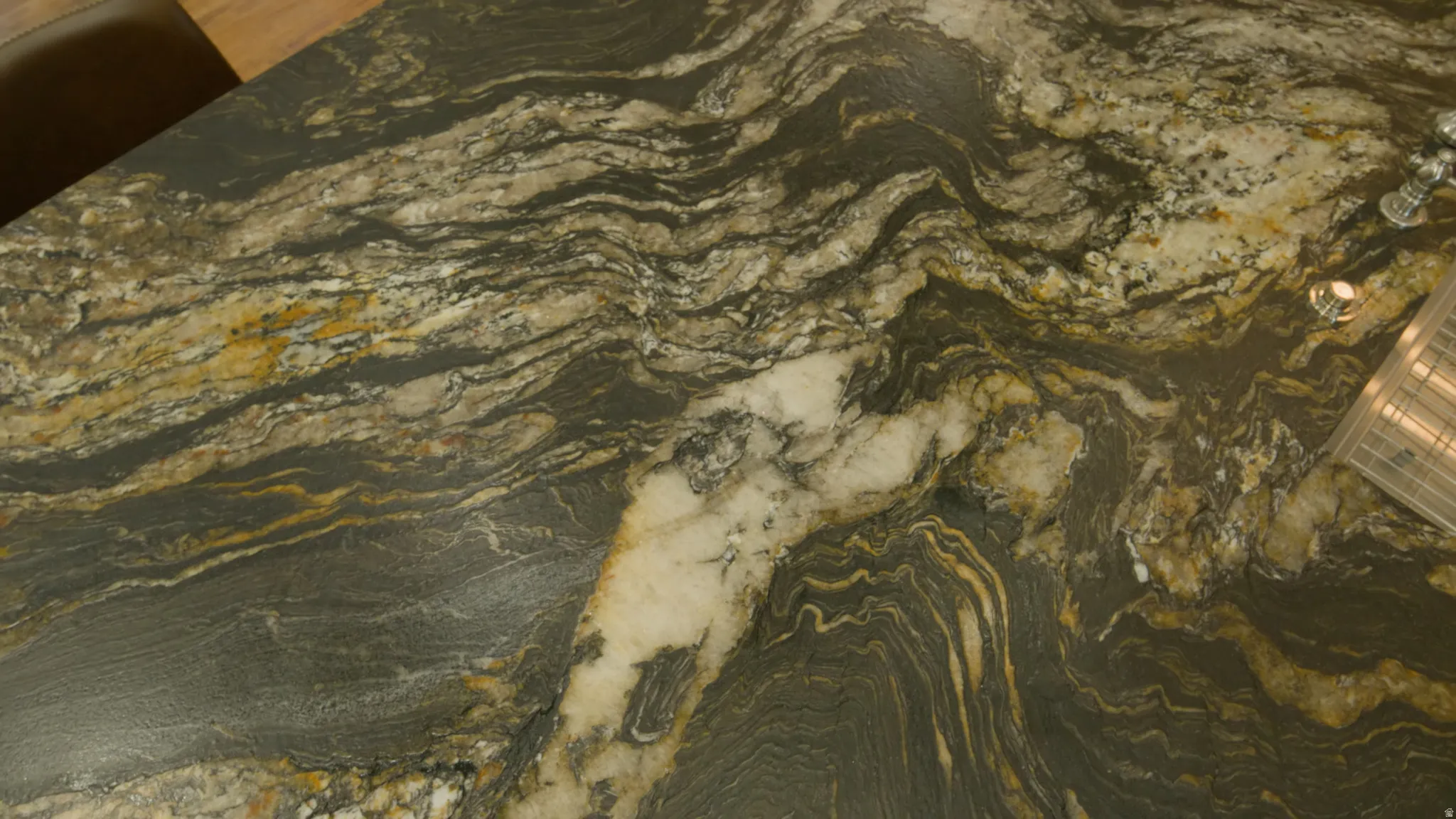 Stone countertop featuring a striking natural pattern with deep gray, gold, and white veining