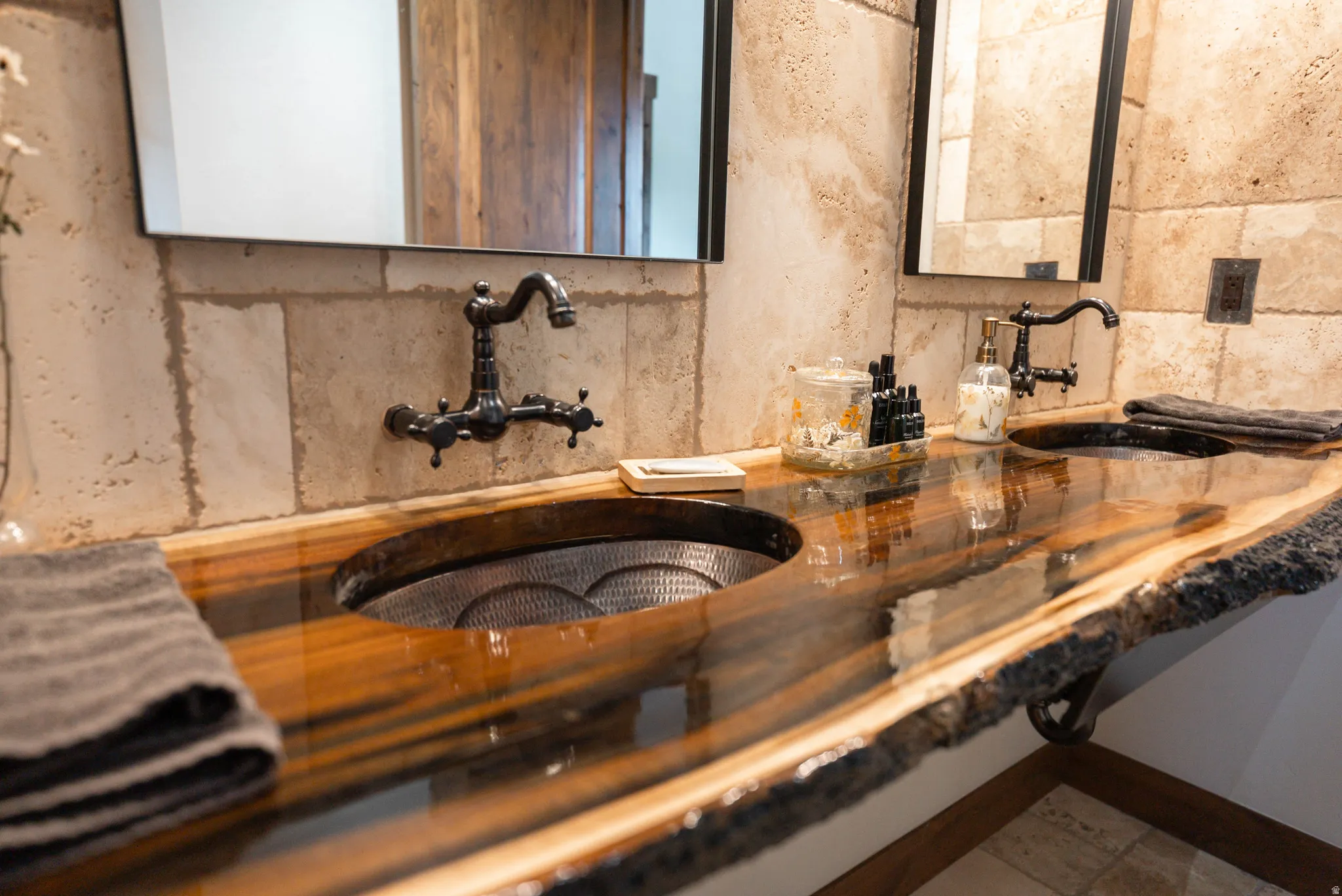 Live edge wood vanity with a high-gloss finish, featuring two vessel sinks with hammered metal interiors