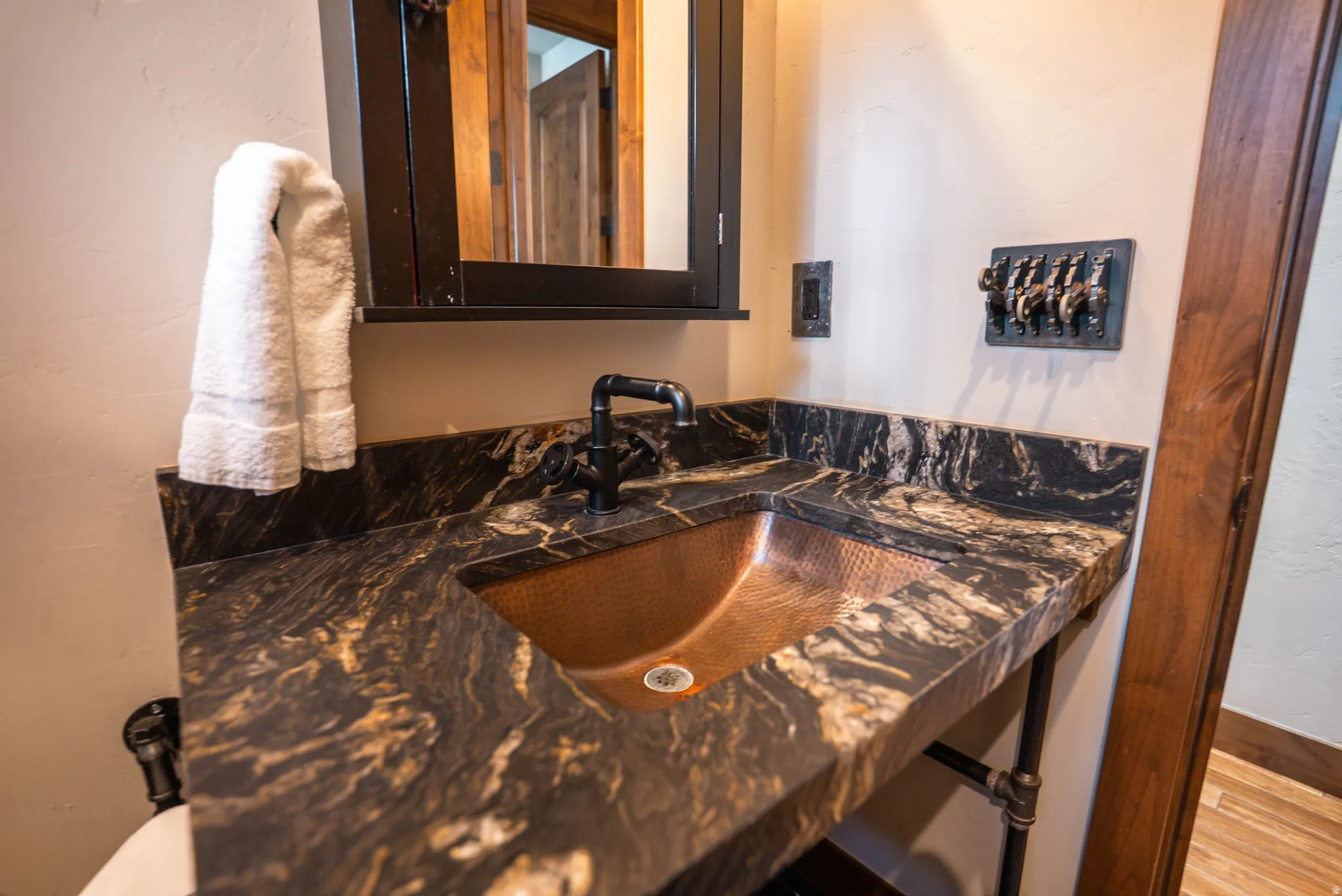 Copper vessel sink set into a dark granite countertop, featuring a matte black faucet