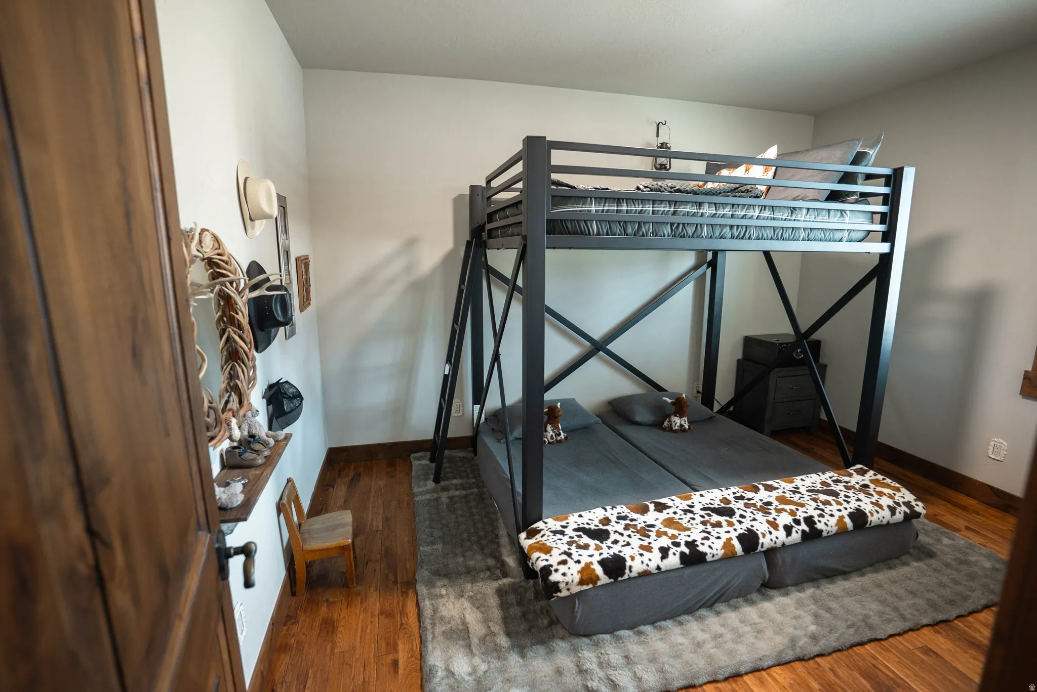 Bedroom featuring rich wood-finish flooring and a contemporary black metal bunk bed