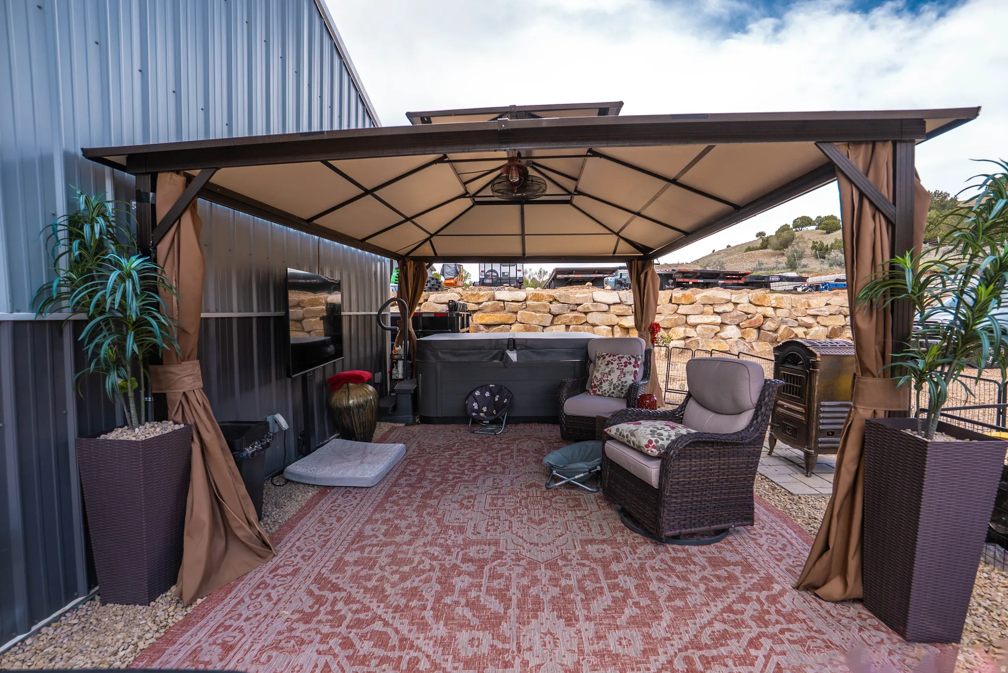 Covered outdoor patio featuring a hot tub, ceiling fan, and privacy curtains