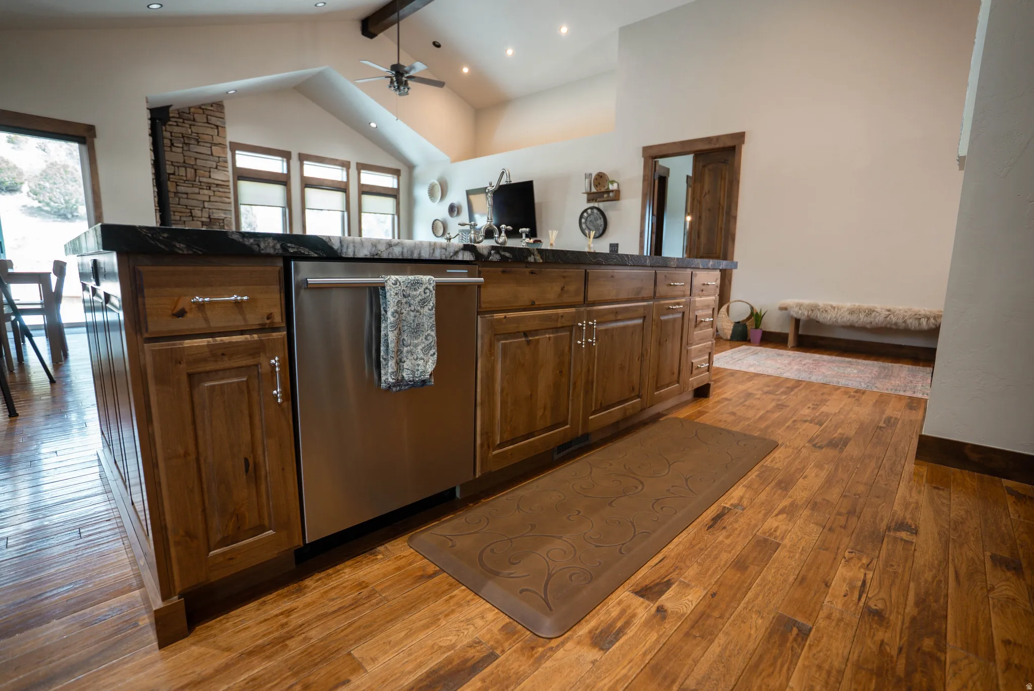 Kitchen island featuring wood-finish cabinetry, a dark countertop, and an integrated stainless steel dishwasher