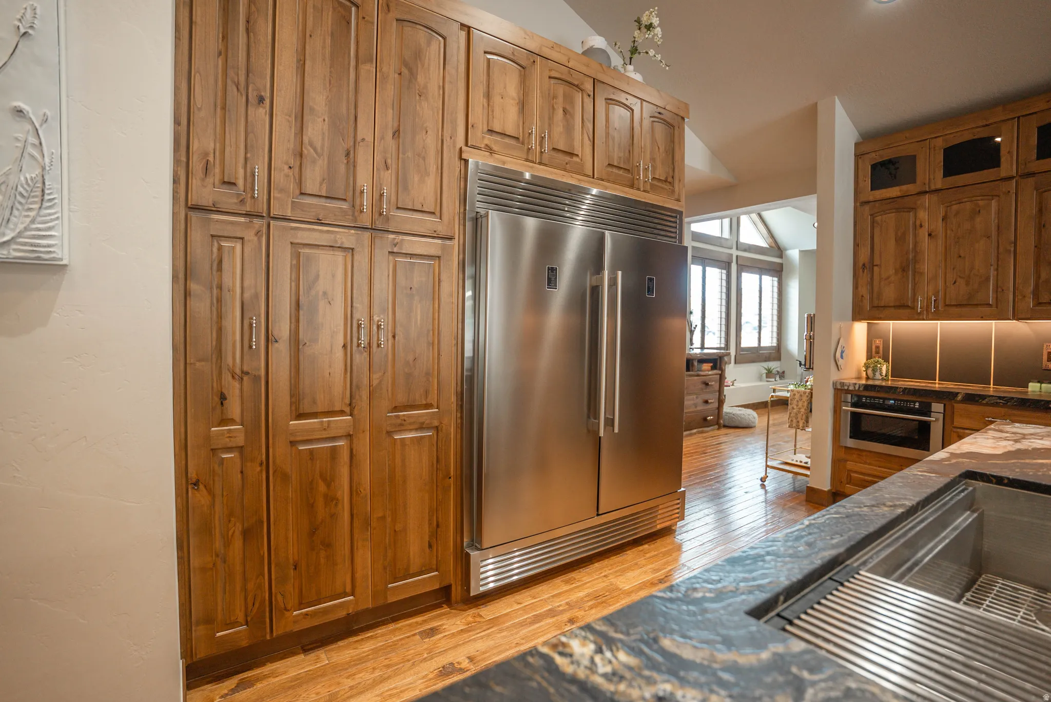 Kitchen featuring extensive wood cabinetry, integrated stainless steel refrigerator, stone countertops, and a built-in oven