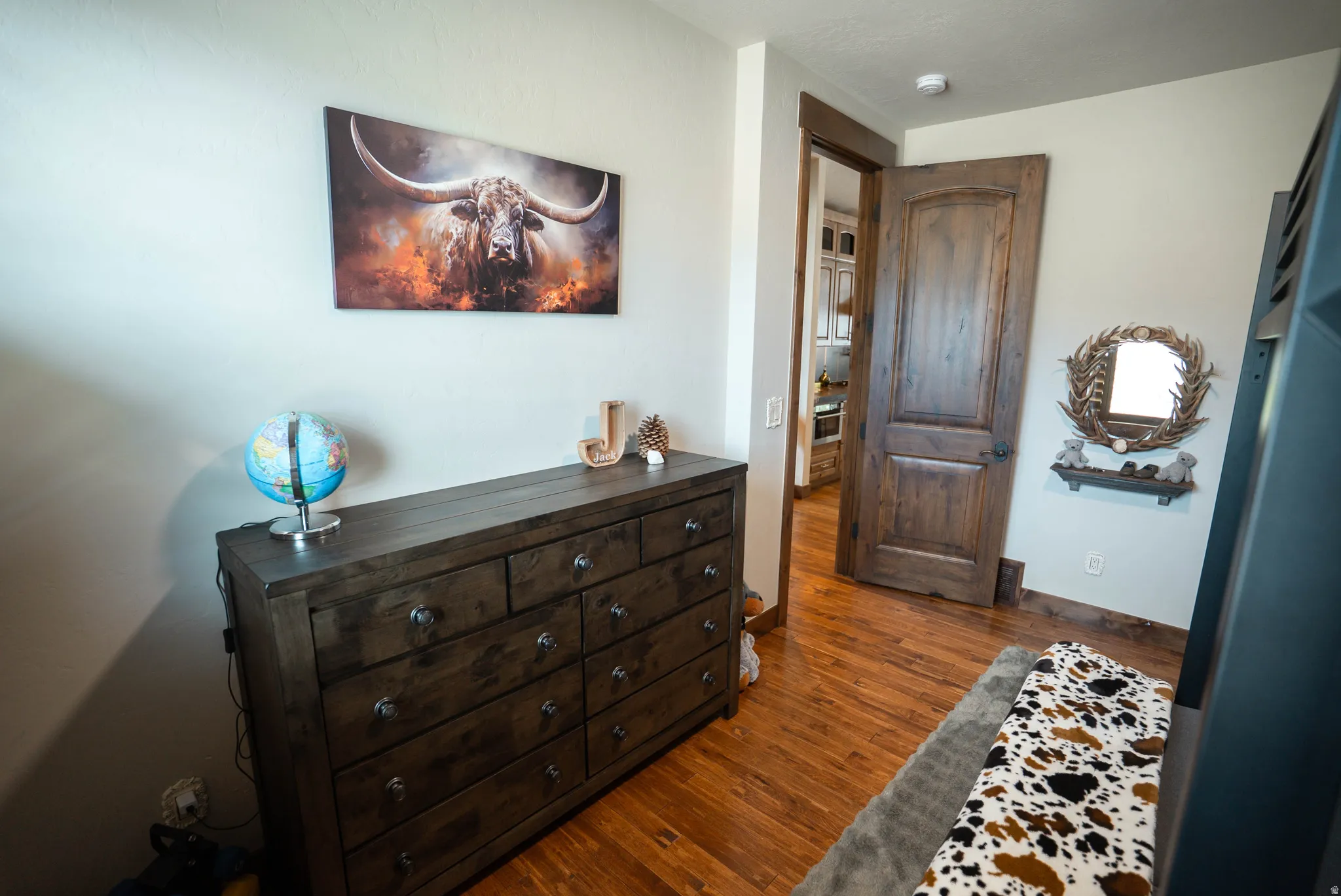 Rich wood-finish flooring complements the solid wood paneled door with dark hardware