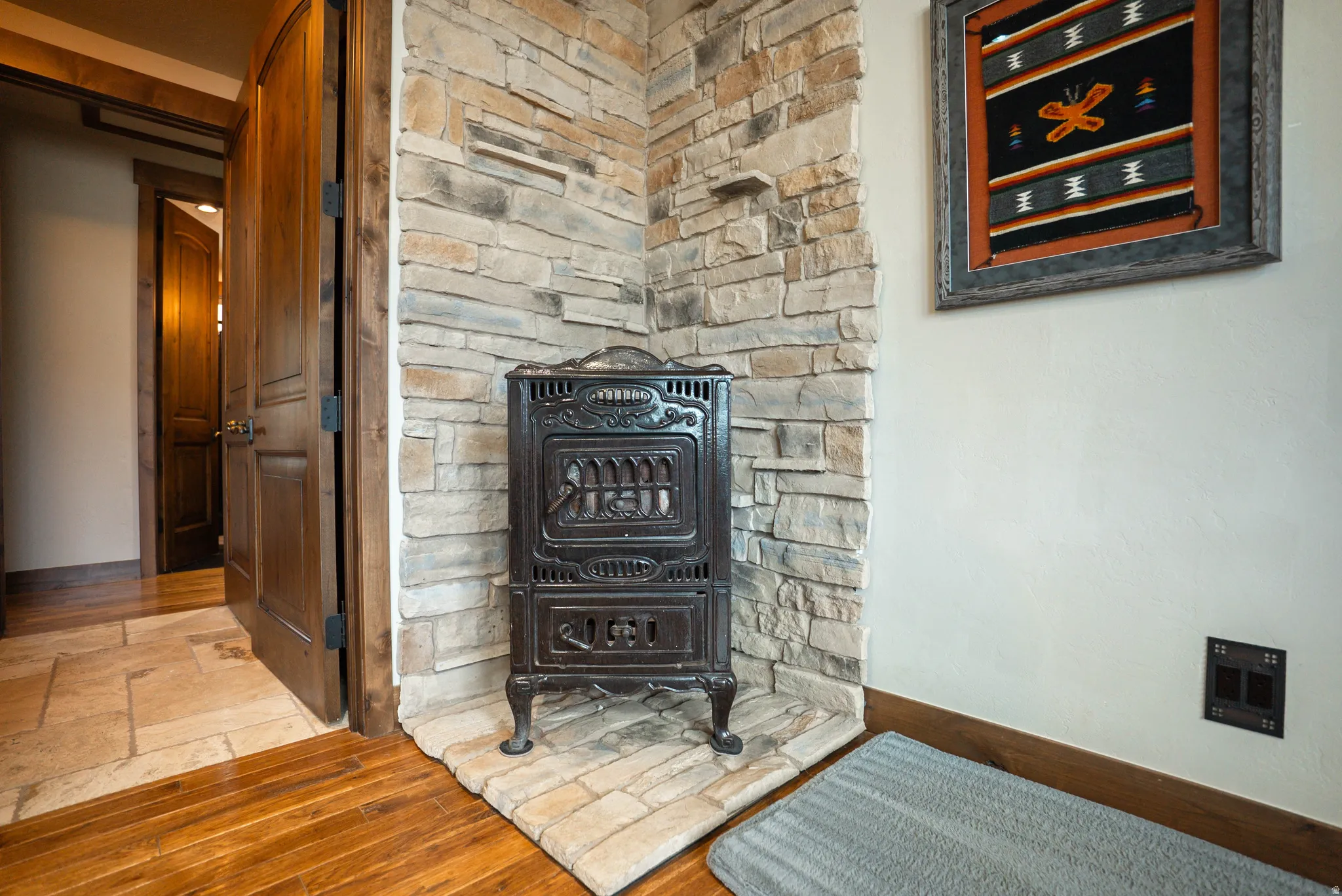 Decorative cast iron stove with a stone hearth and full-height stone wall accent