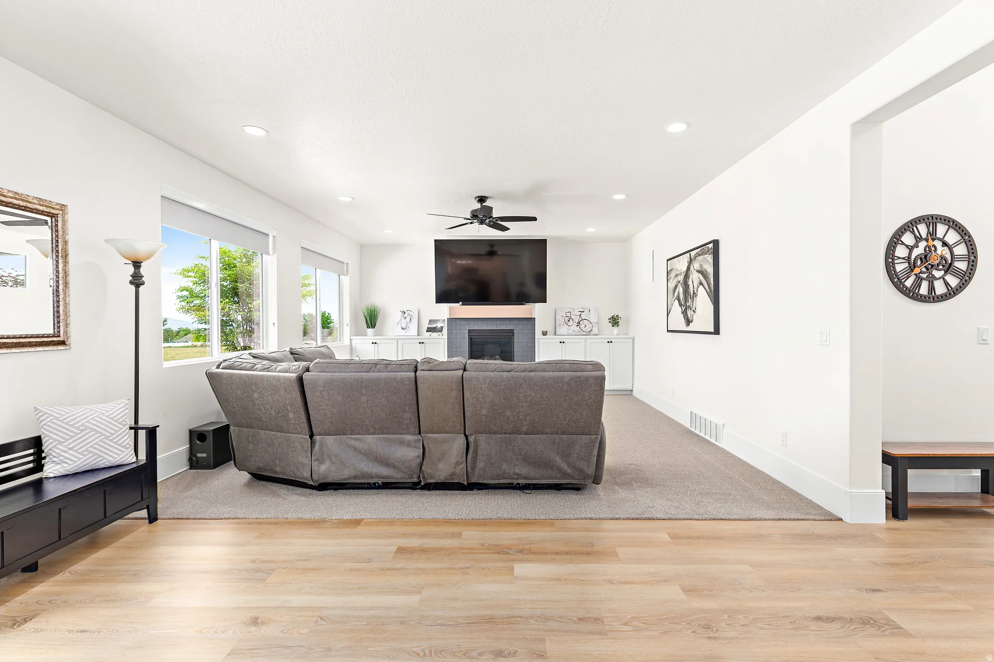 Open-concept living space featuring wood-finish flooring extending to a carpeted area