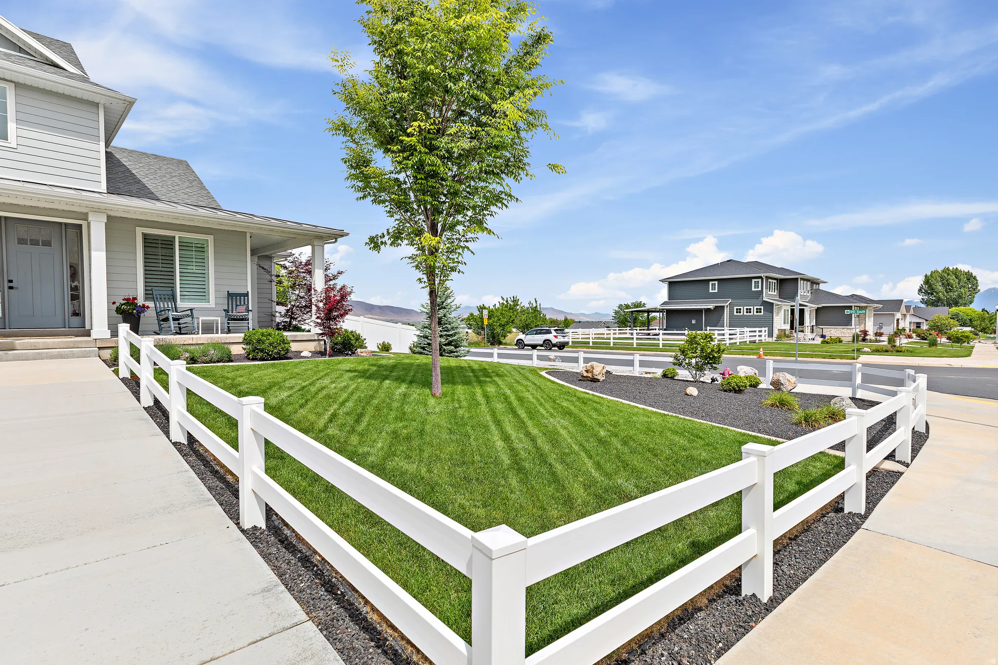 Manicured front lawn with a white split-rail fence