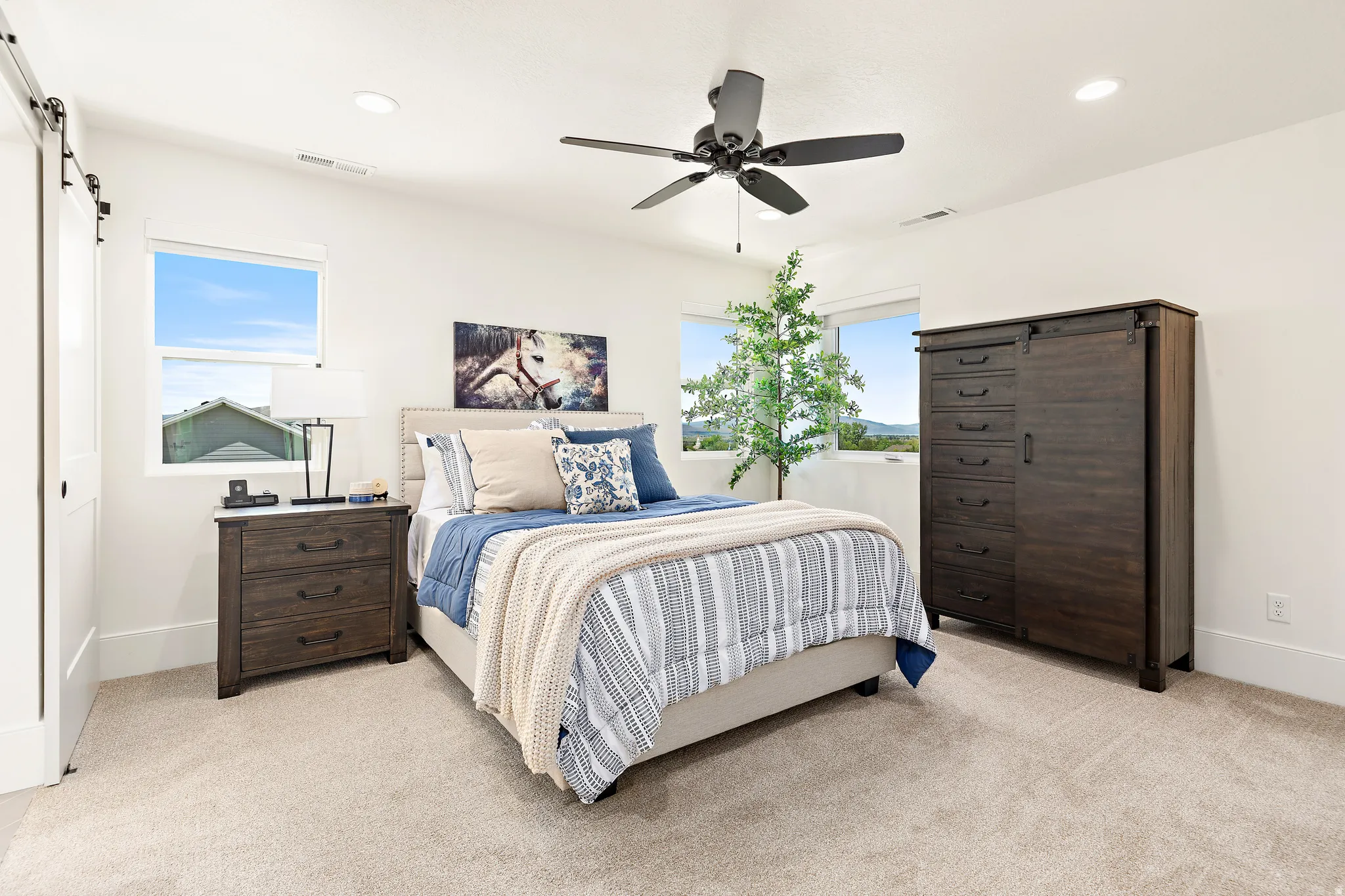 Carpeted room featuring a ceiling fan, recessed lighting, and multiple windows