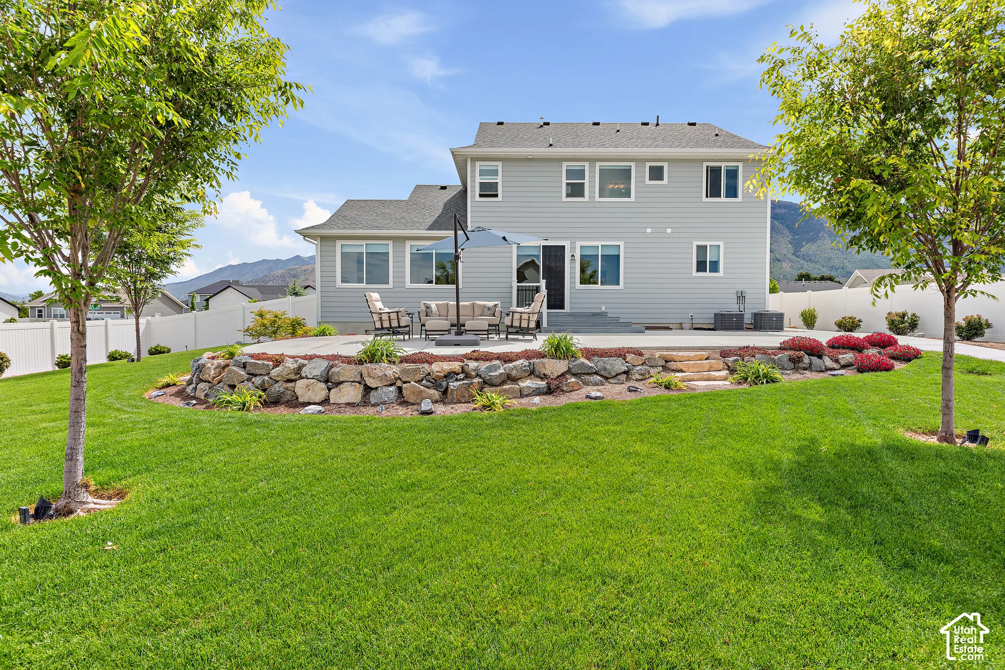 Expansive backyard featuring a manicured lawn, a multi-level patio, and a stone retaining wall