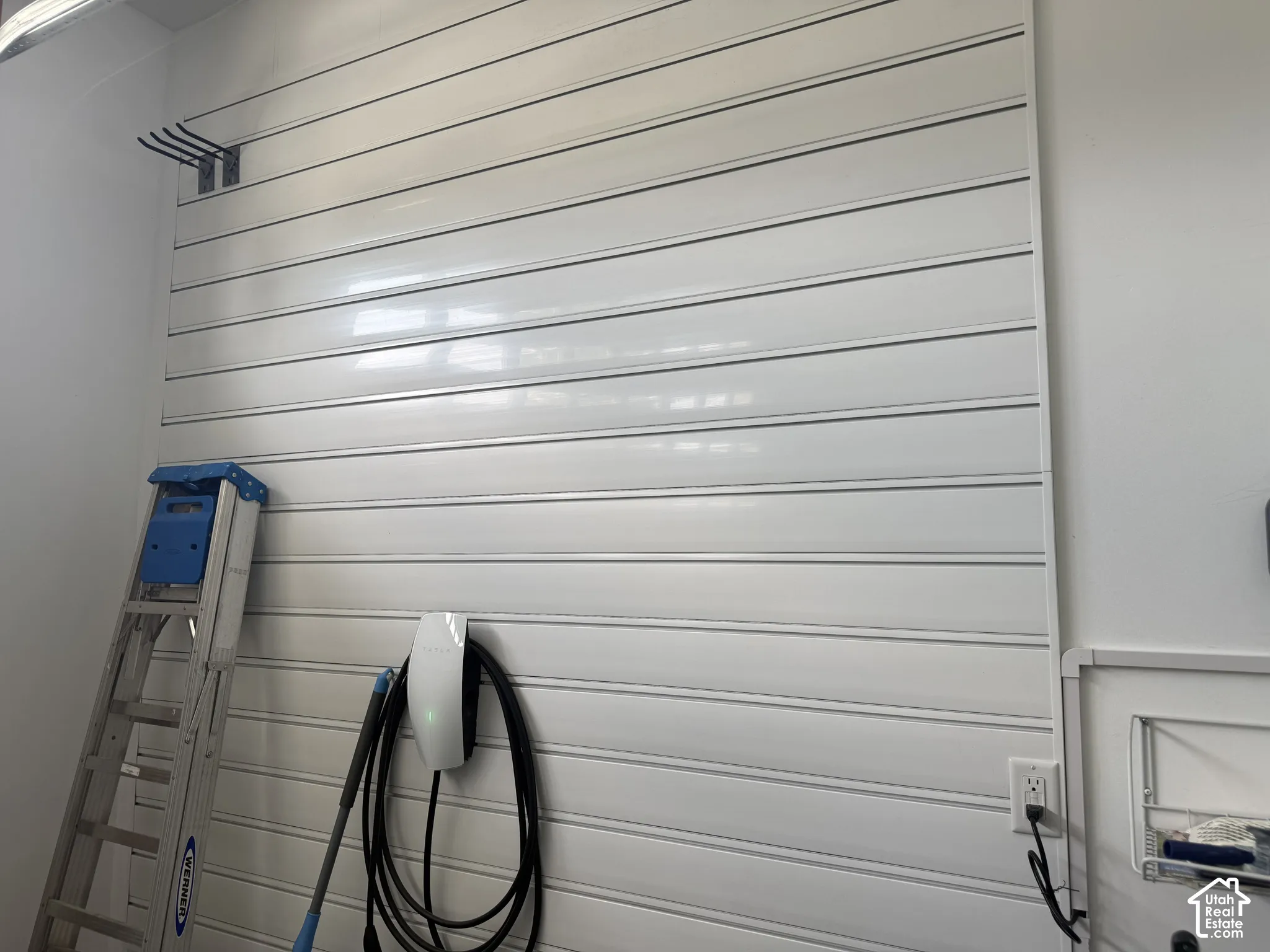 Wall-mounted slat paneling for organization of large tools with an integrated electric vehicle charging station
