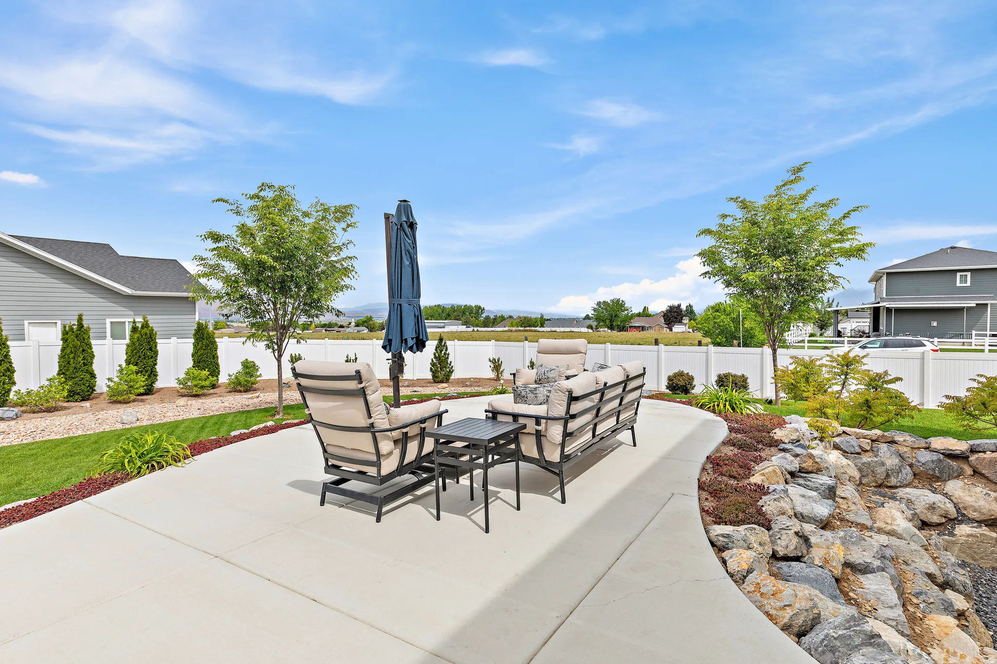 Curved concrete patio alongside a rock garden with varied plantings