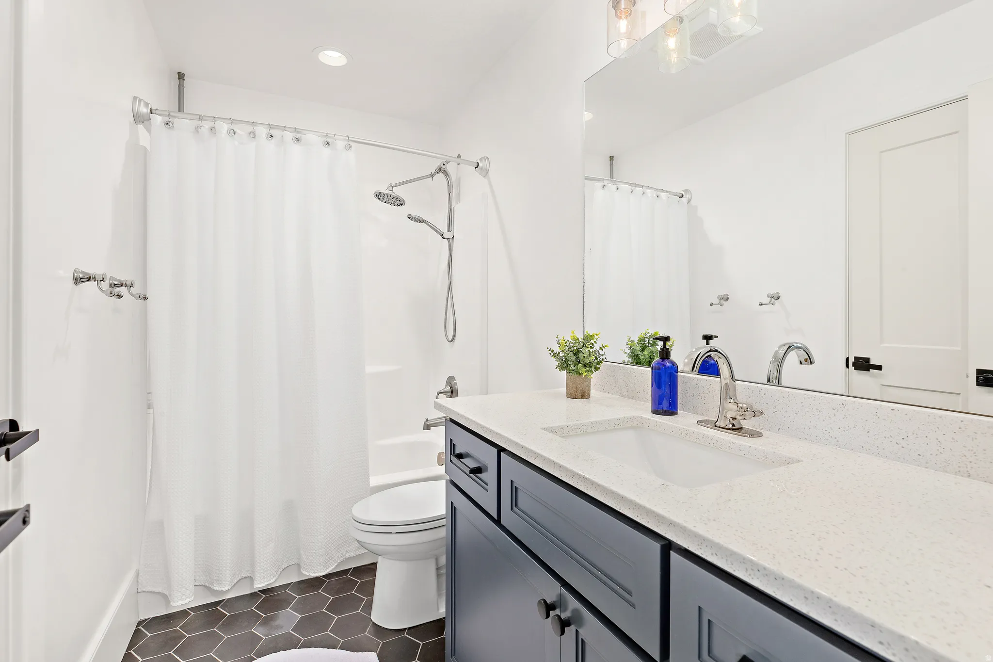 Bathroom featuring a vanity with a light-toned countertop and integrated sink, dark cabinetry, and chrome fixtures