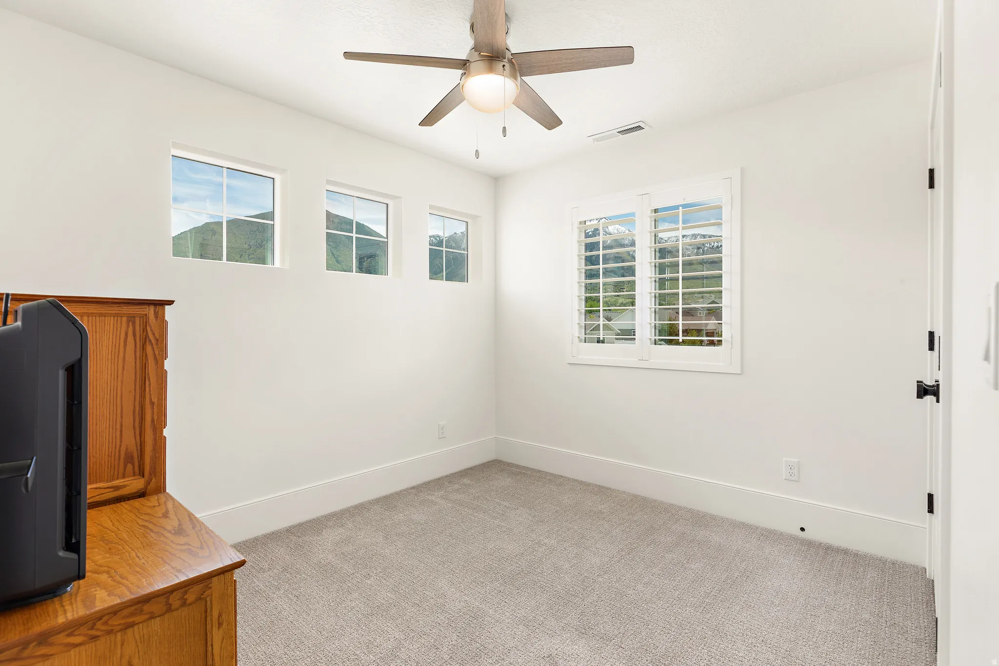 Room featuring light gray carpet, white walls, and a ceiling fan