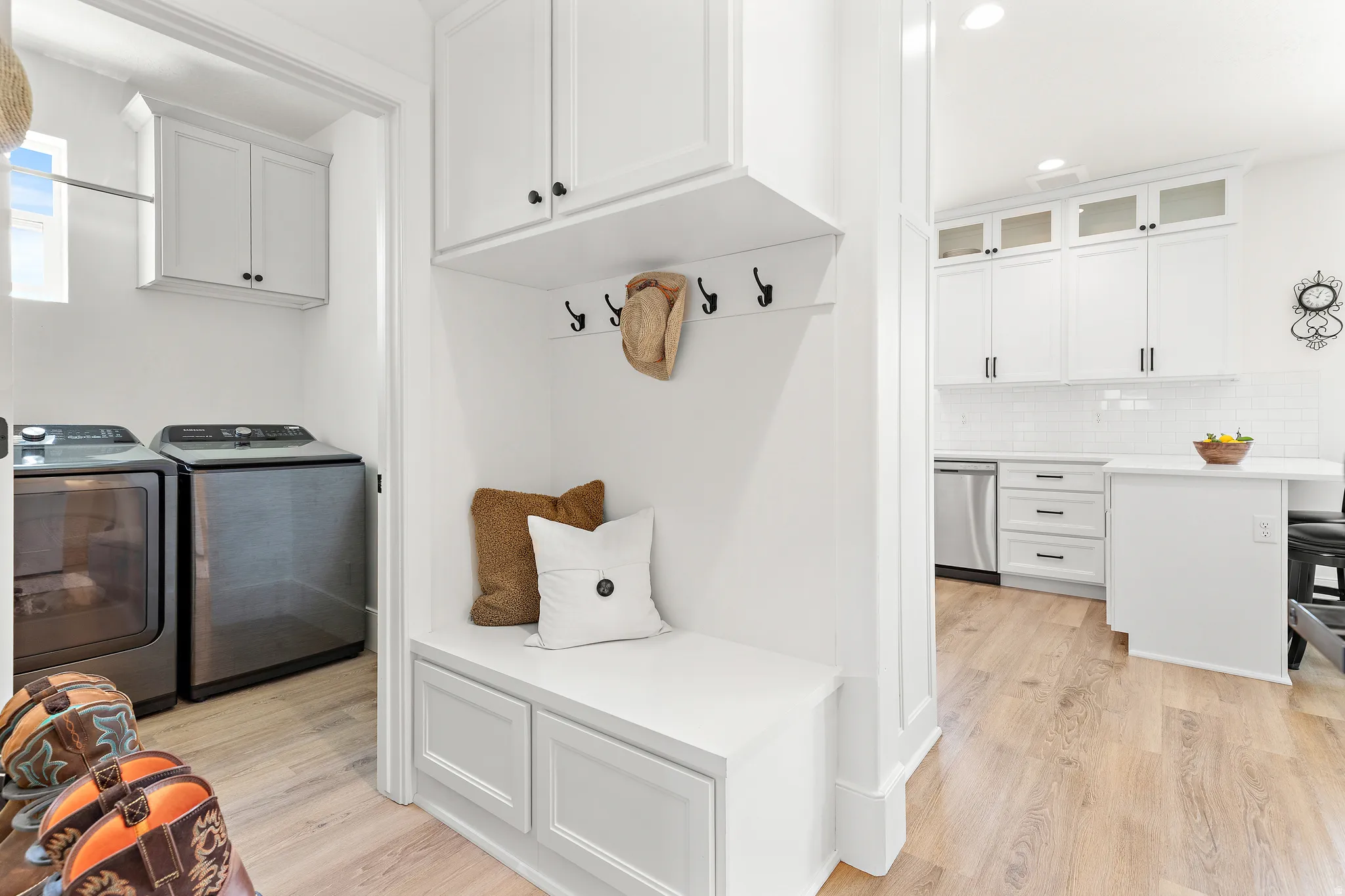 Built-in mudroom bench with storage, upper cabinetry, and coat hooks