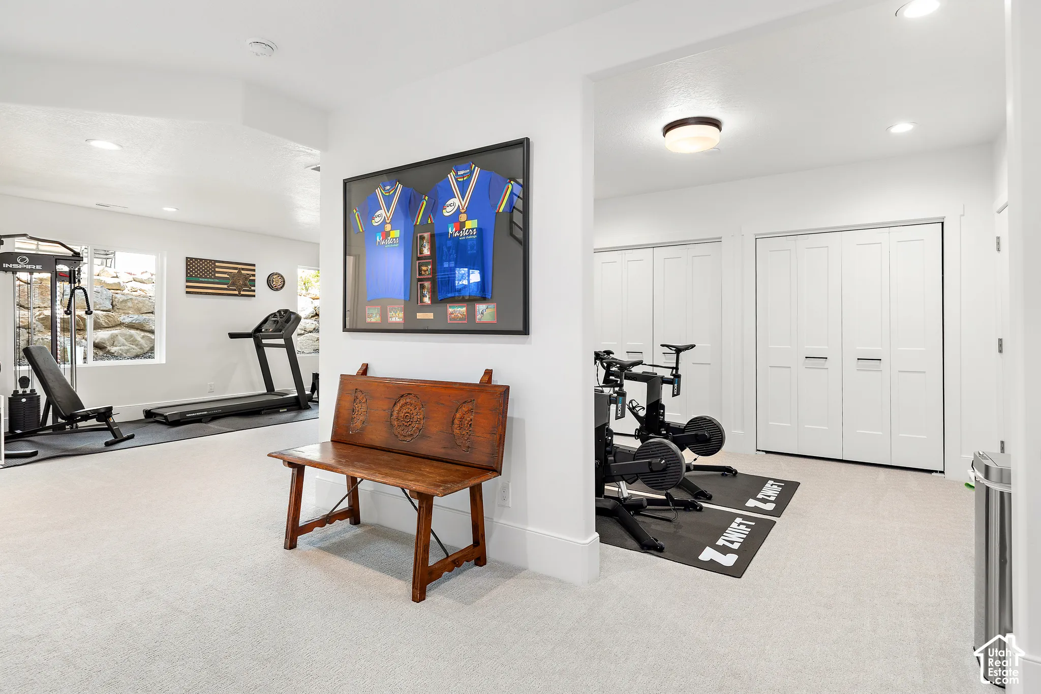 Spacious lower-level area featuring light-colored carpeting, recessed lighting, and bright white walls