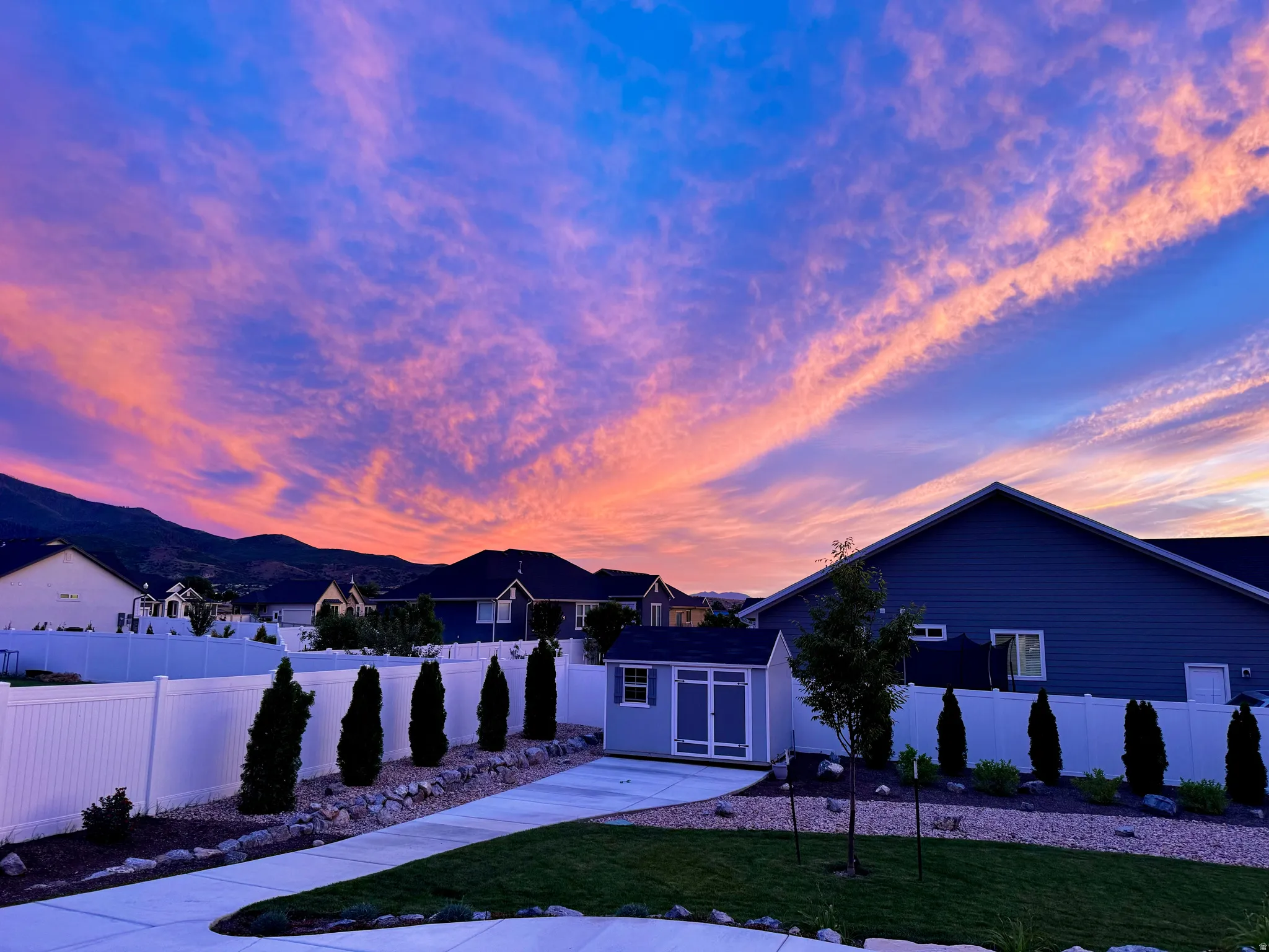 Expansive outdoor space featuring a manicured lawn, concrete patio, and a white privacy fence