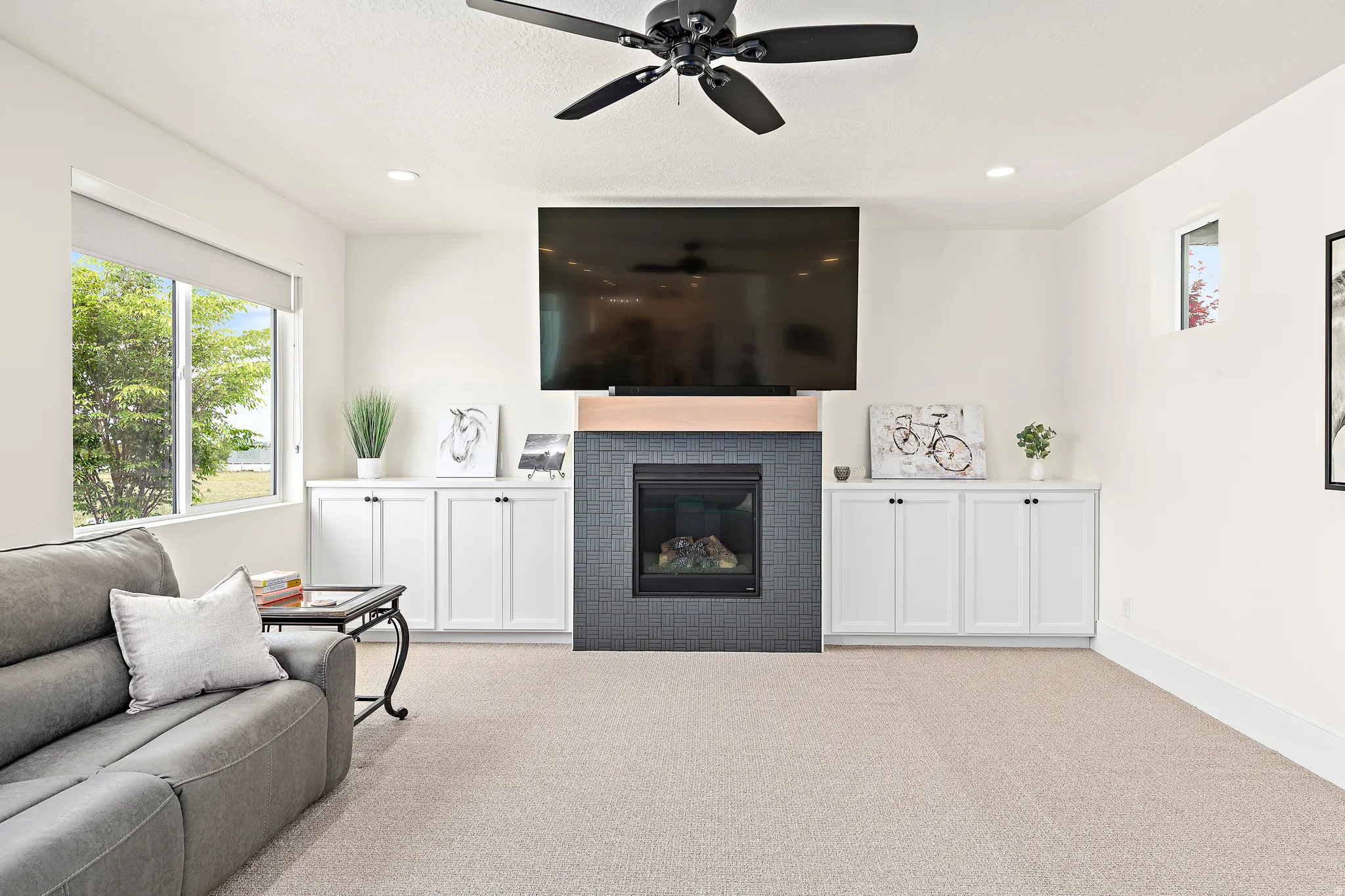 Living area featuring a gas fireplace with dark tile surround and wood mantel, integrated built-in cabinetry, recessed lighting, and a ceiling fan