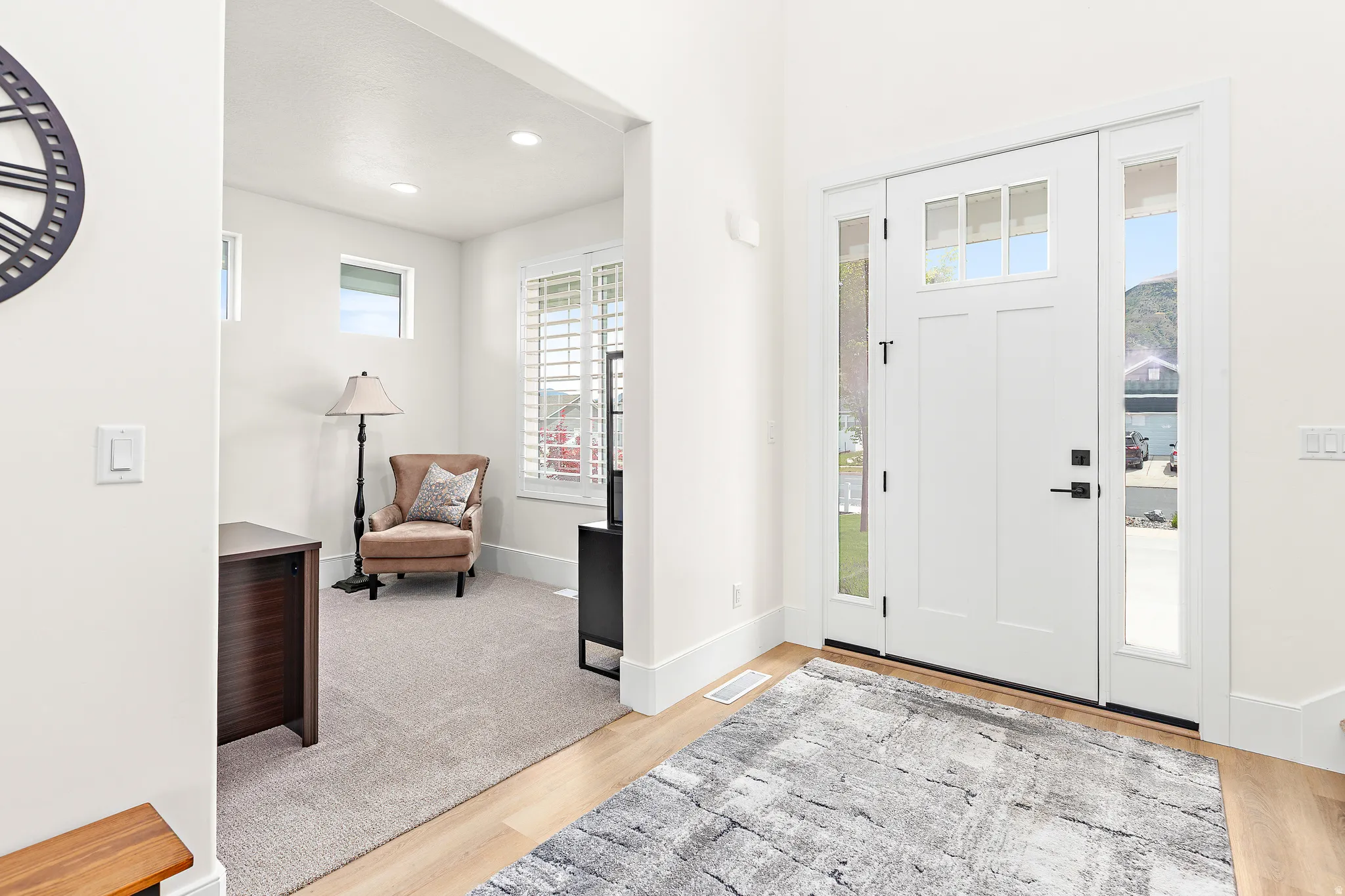 Entryway featuring a white paneled door with glass inserts, flanked by matching sidelight windows, and light wood-finish flooring