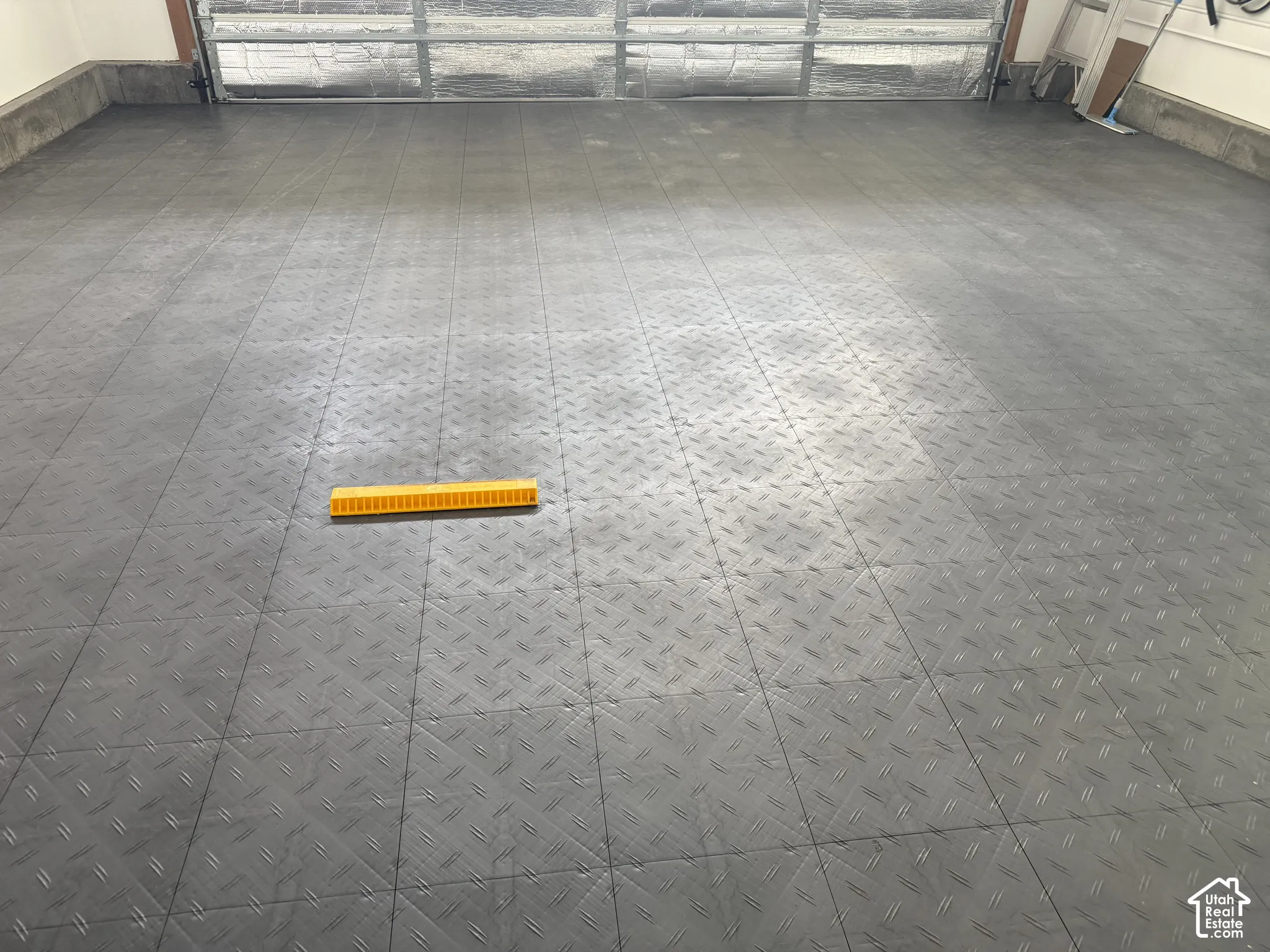 Garage featuring a patterned protective flooring and automatic insulated garage door helps save energy.