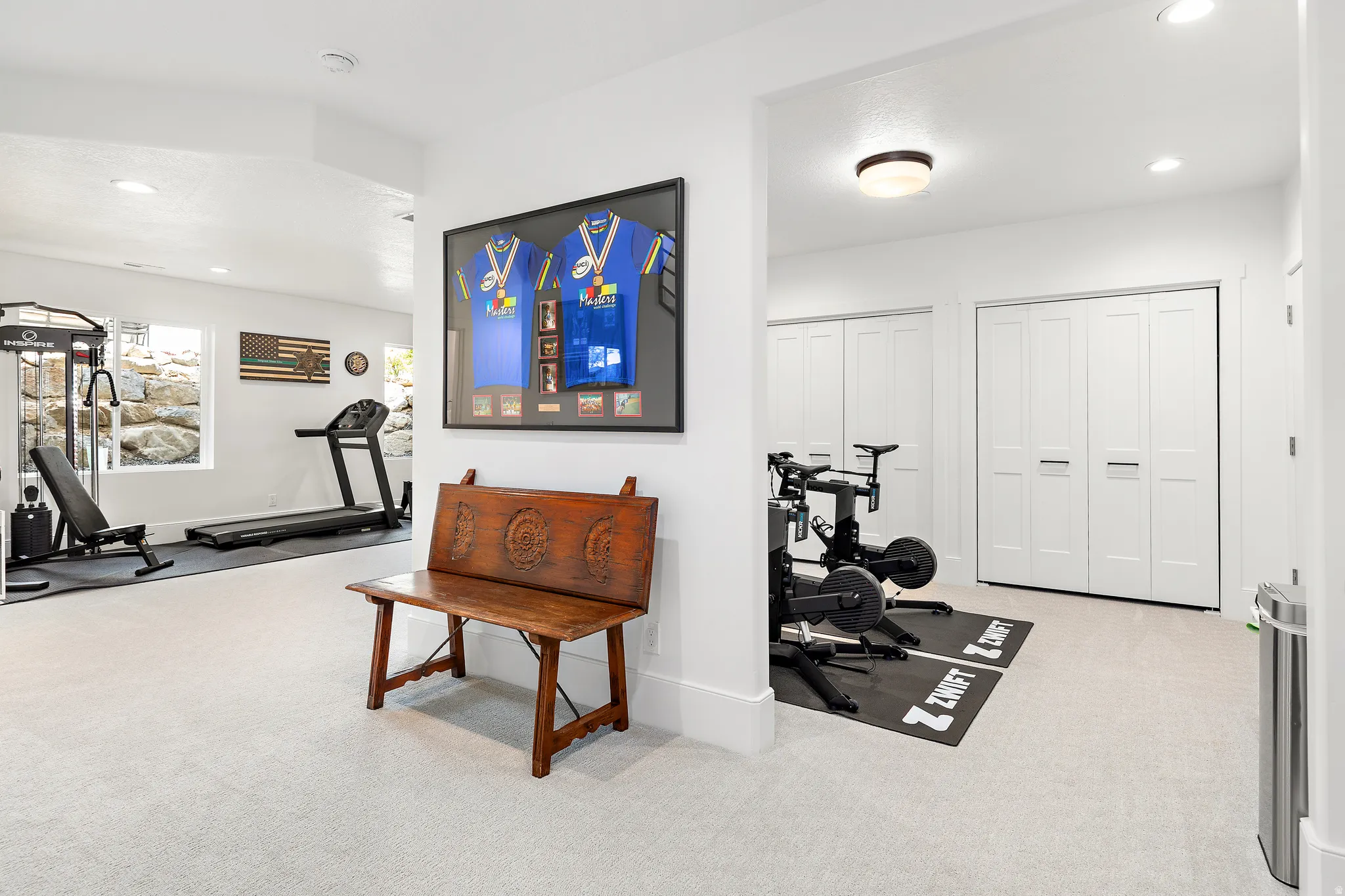Spacious lower-level area featuring light-colored carpeting, recessed lighting, and bright white walls