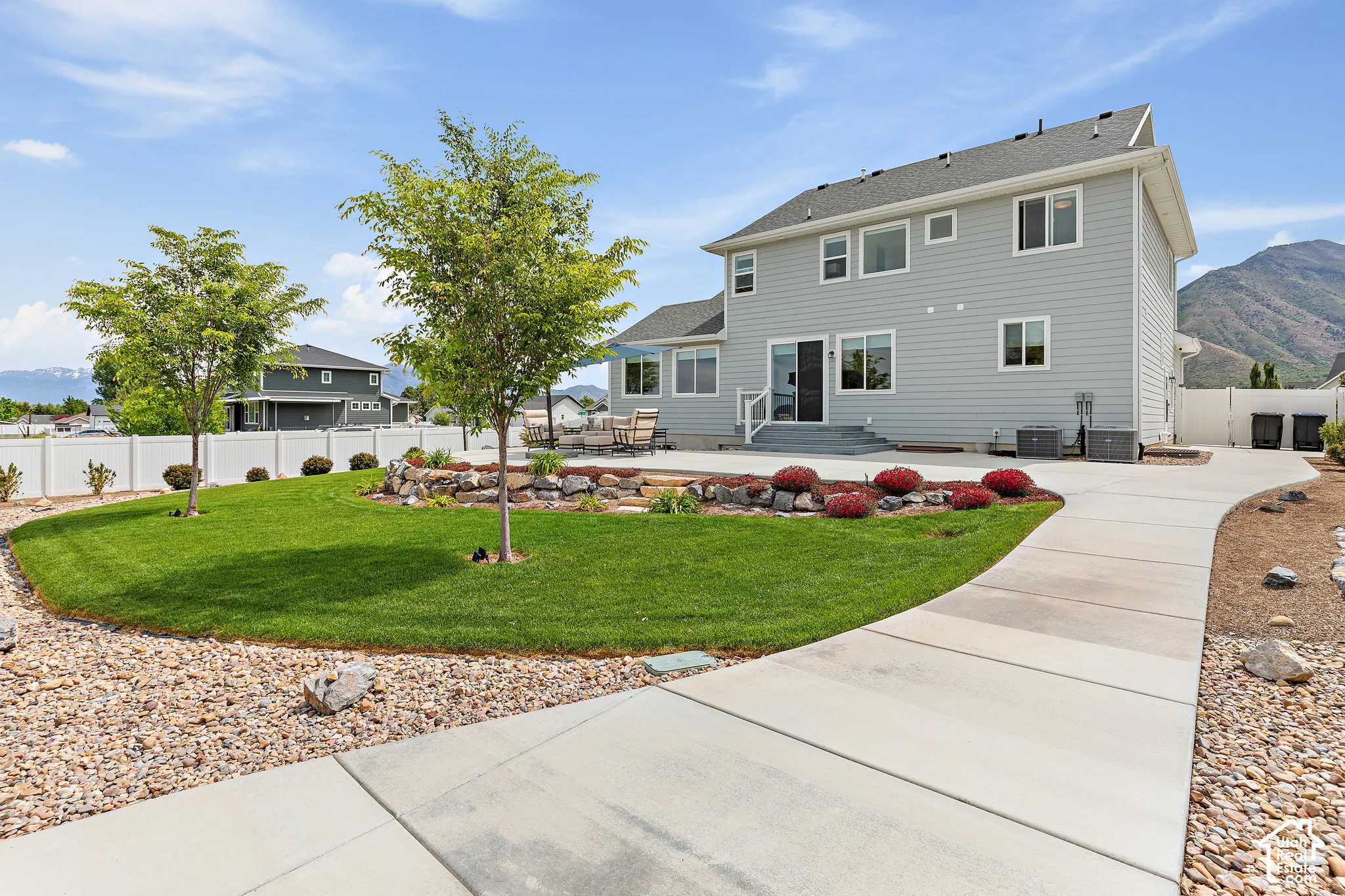 Expansive backyard featuring a manicured lawn, concrete patio, and mature trees