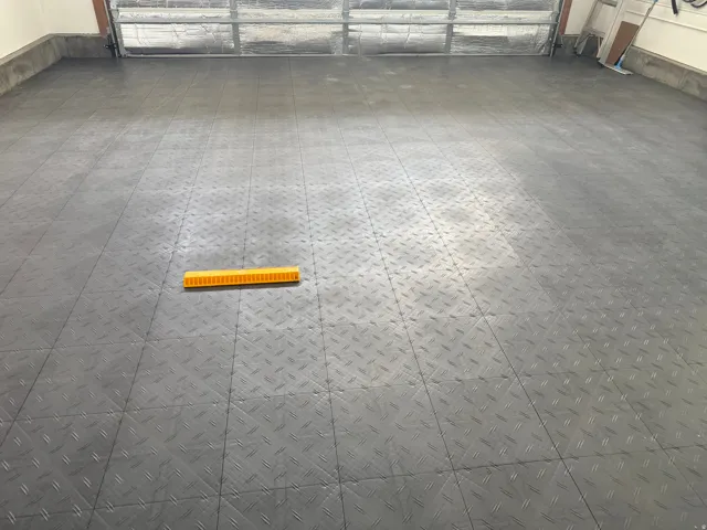 Garage featuring a patterned protective flooring and automatic insulated garage door helps save energy.
