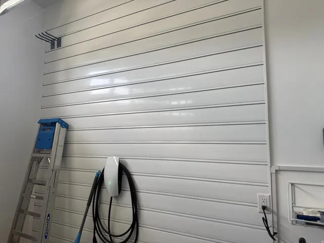 Wall-mounted slat paneling for organization of large tools with an integrated electric vehicle charging station
