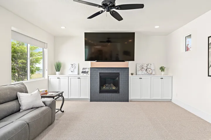 Living area featuring a gas fireplace with dark tile surround and wood mantel, integrated built-in cabinetry, recessed lighting, and a ceiling fan