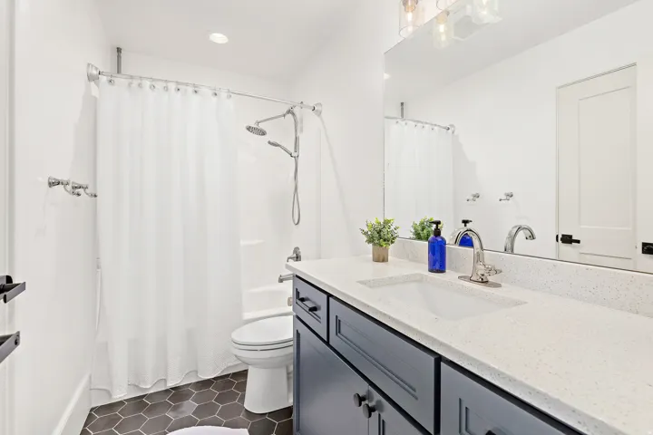 Bathroom featuring a vanity with a light-toned countertop and integrated sink, dark cabinetry, and chrome fixtures