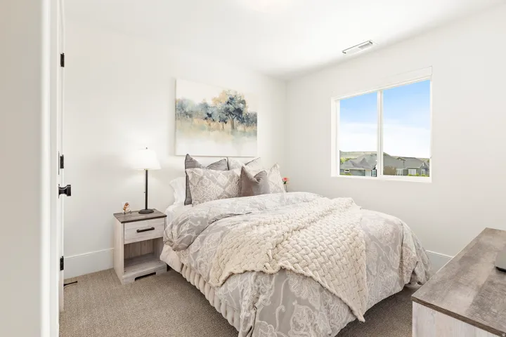 Bright bedroom featuring a large window, plush carpet, and a neutral color palette