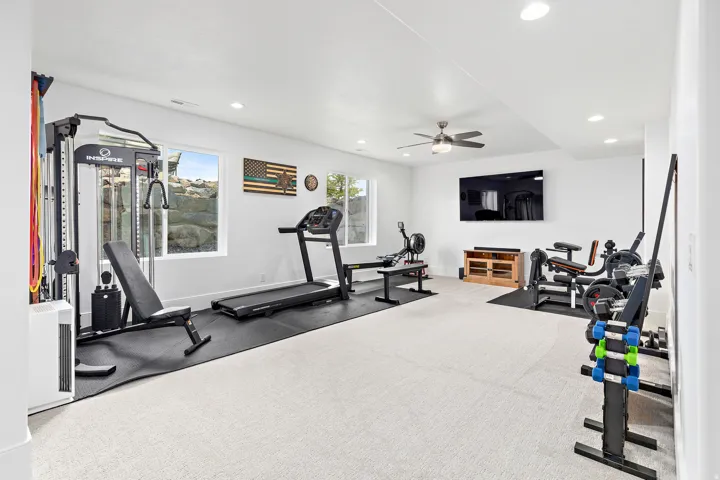 Spacious room featuring light-colored carpet flooring, recessed lighting, and a ceiling fan