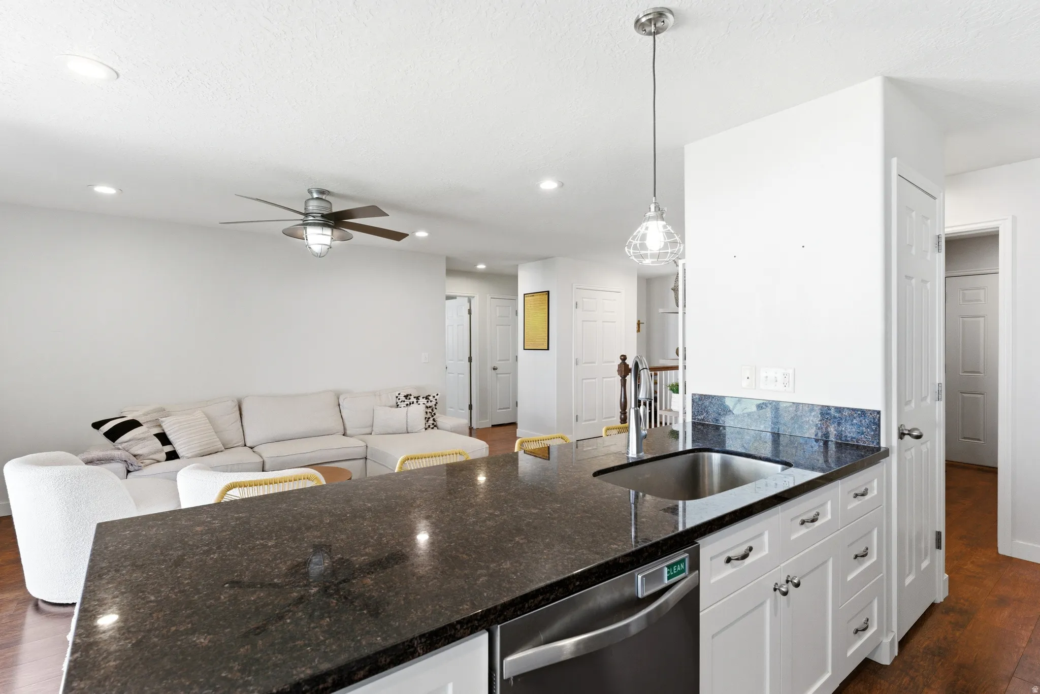 Kitchen island featuring a stainless steel sink and dark countertop
