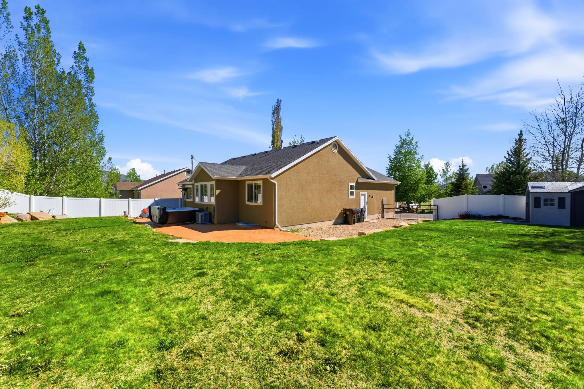 Expansive green lawn with a white privacy fence