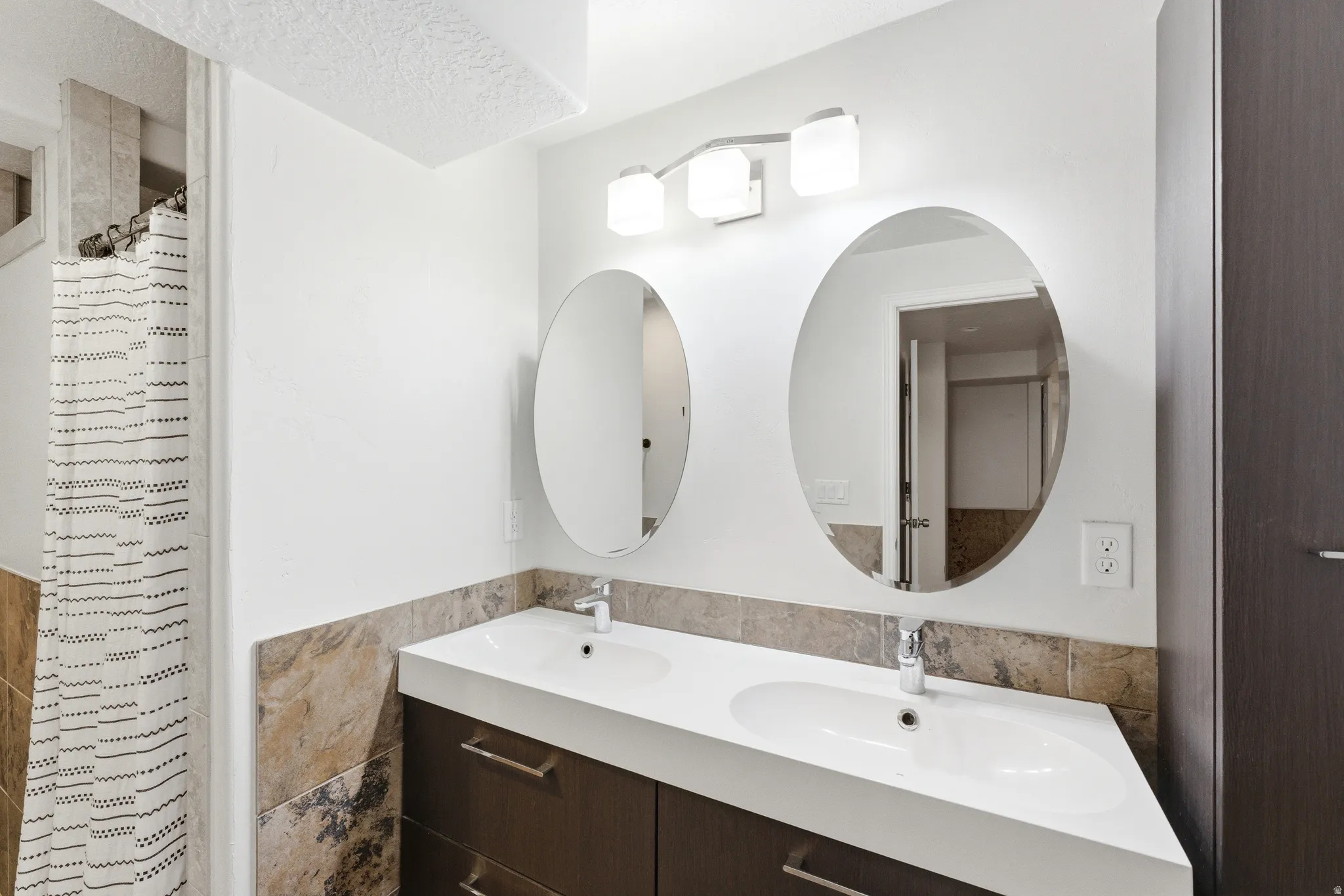 Dual oval mirrors above a contemporary double vanity with integrated sinks