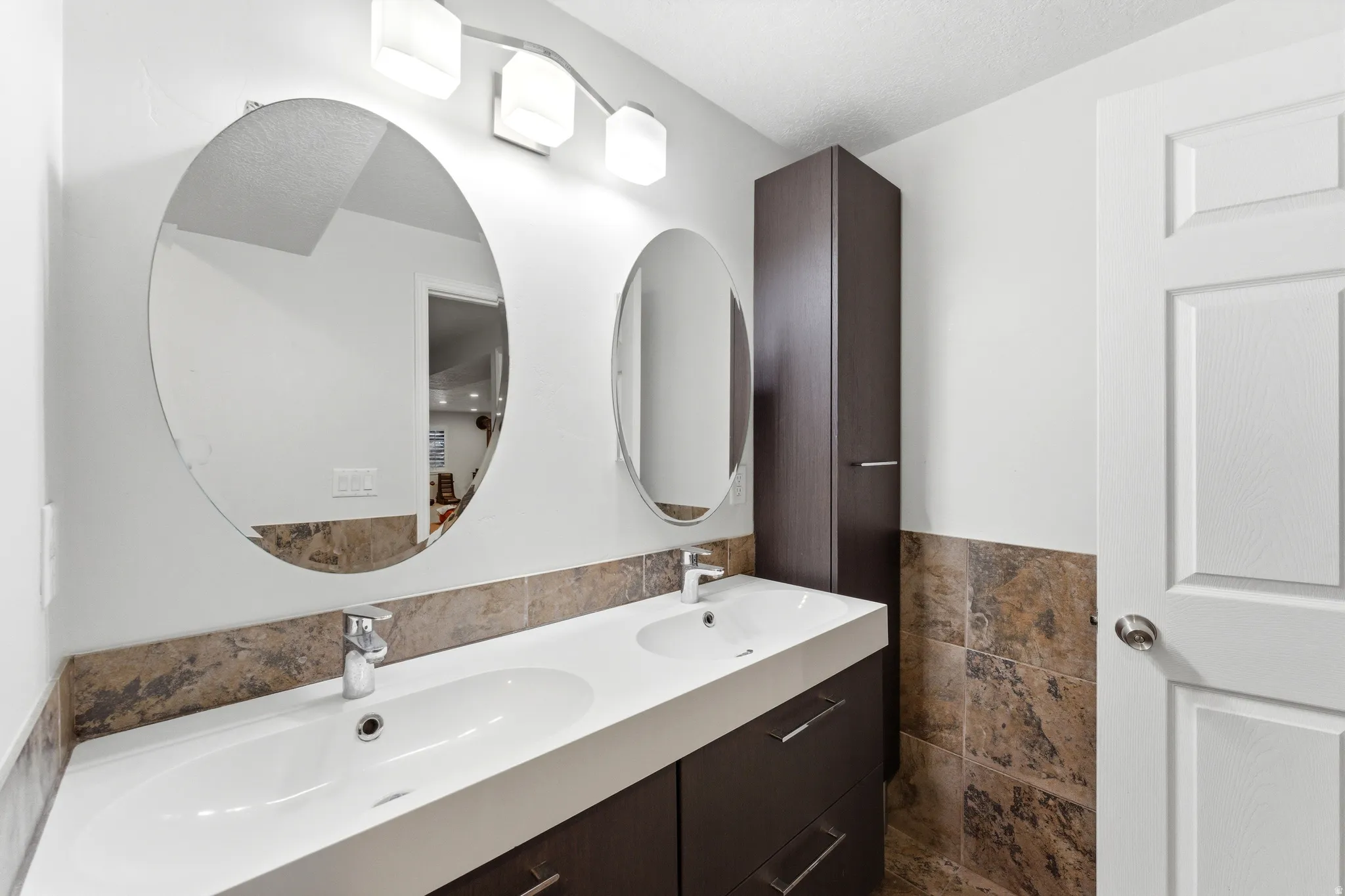 Double vanity with integrated sinks, two round mirrors, and chrome fixtures