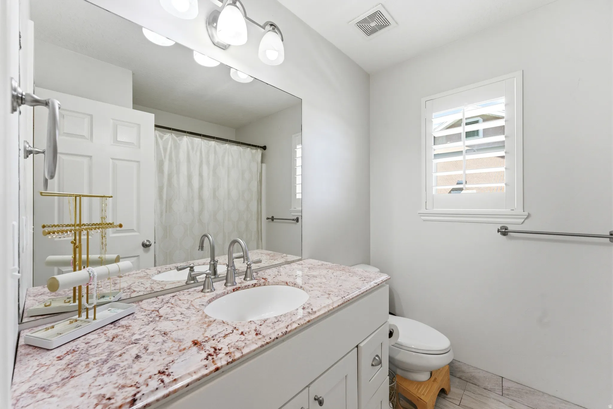Full vanity featuring a single undermount sink, dual polished chrome faucets, and a speckled countertop