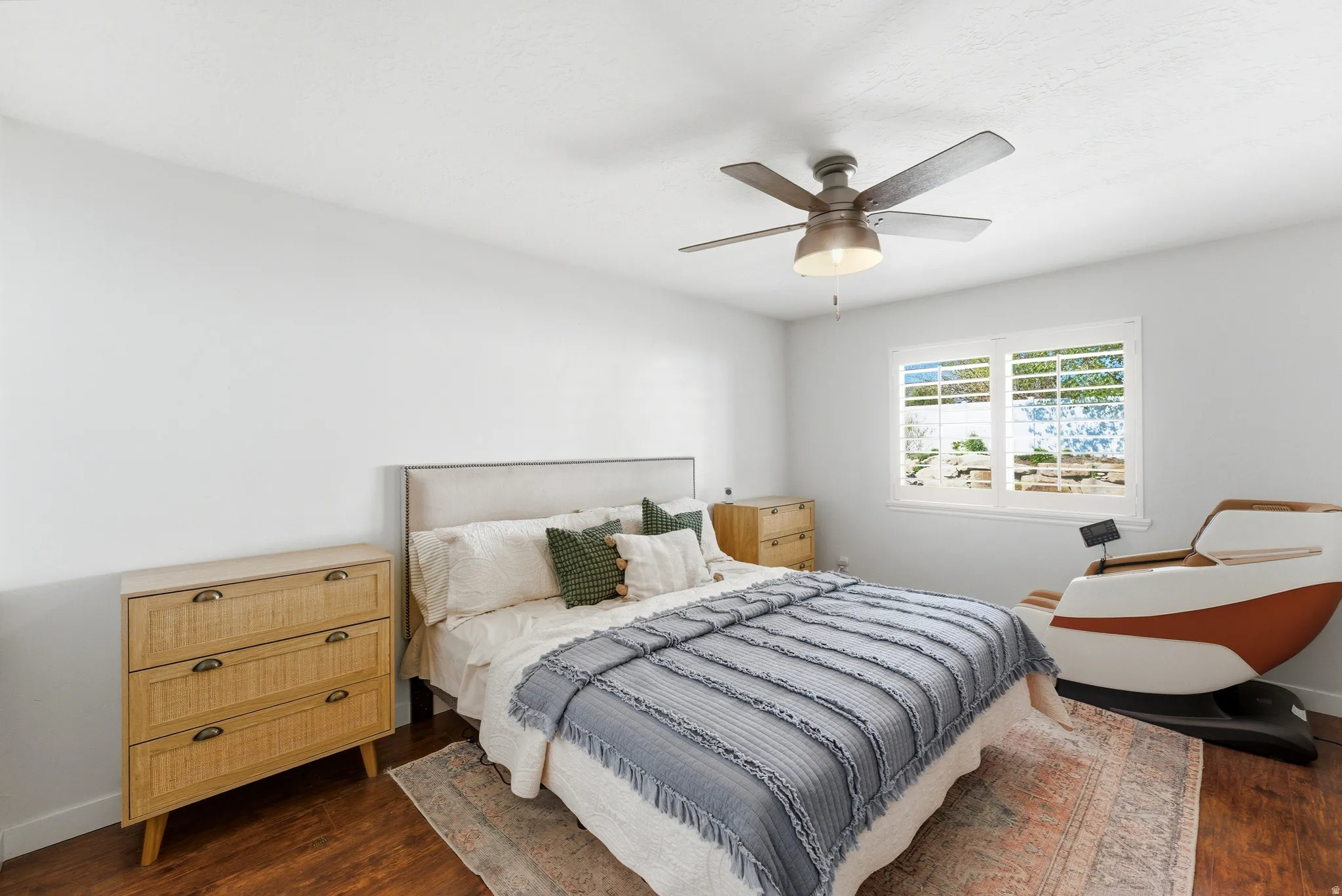 Spacious room featuring wood-finish flooring, a contemporary ceiling fan with integrated lighting, and a window with white louvered blinds
