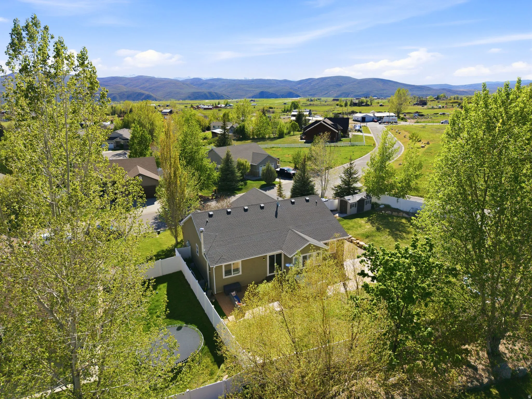 Aerial view of a residential property featuring a muted green exterior with a dark roof