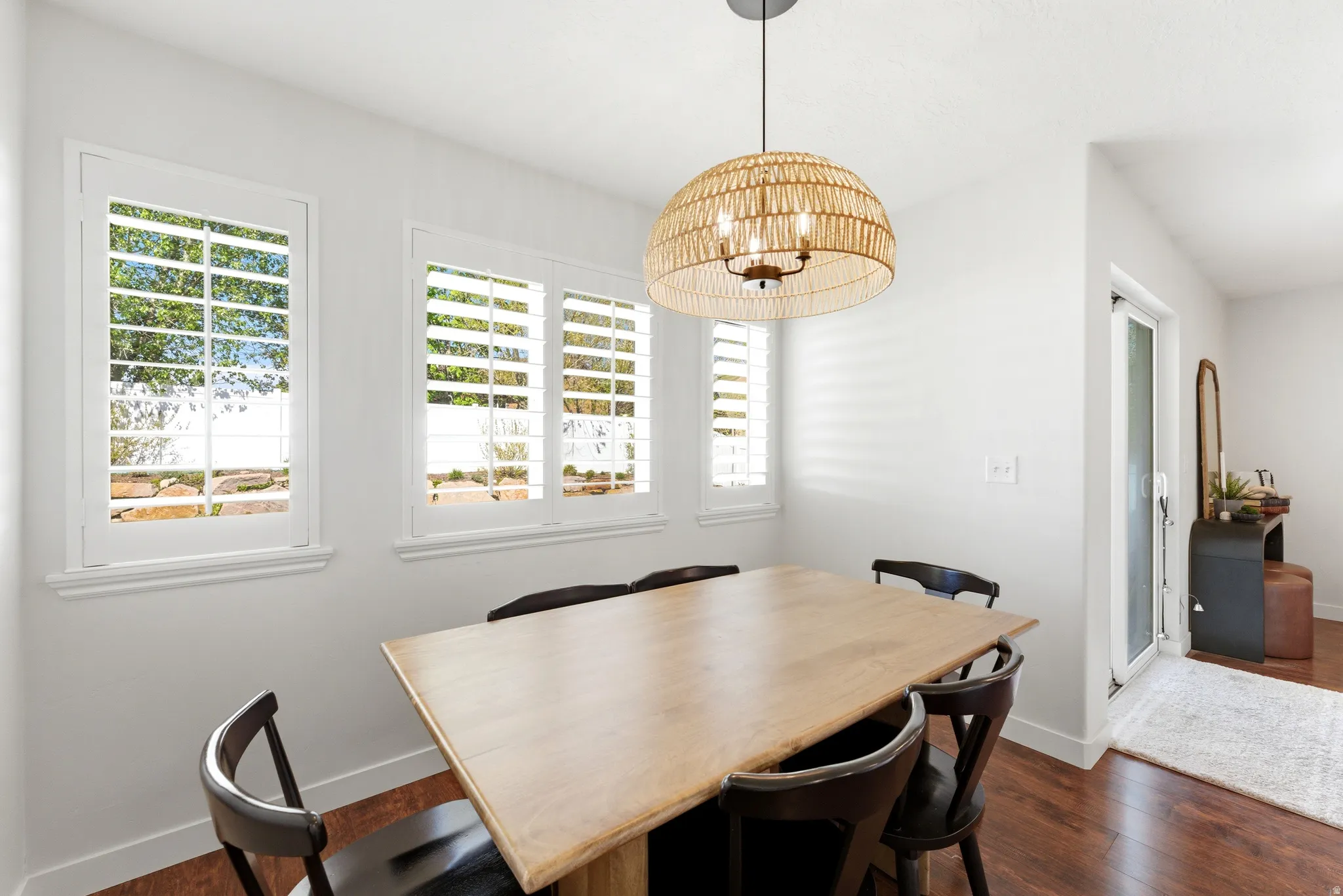 Dining space featuring wood-finish flooring and a woven pendant light fixture