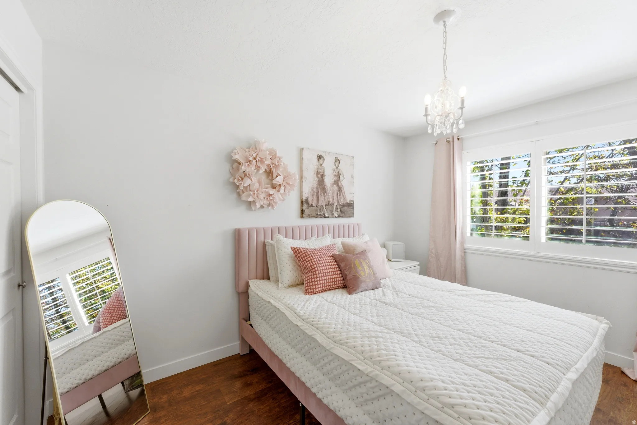 Bright room with wood-finish flooring featuring a window with white plantation shutters