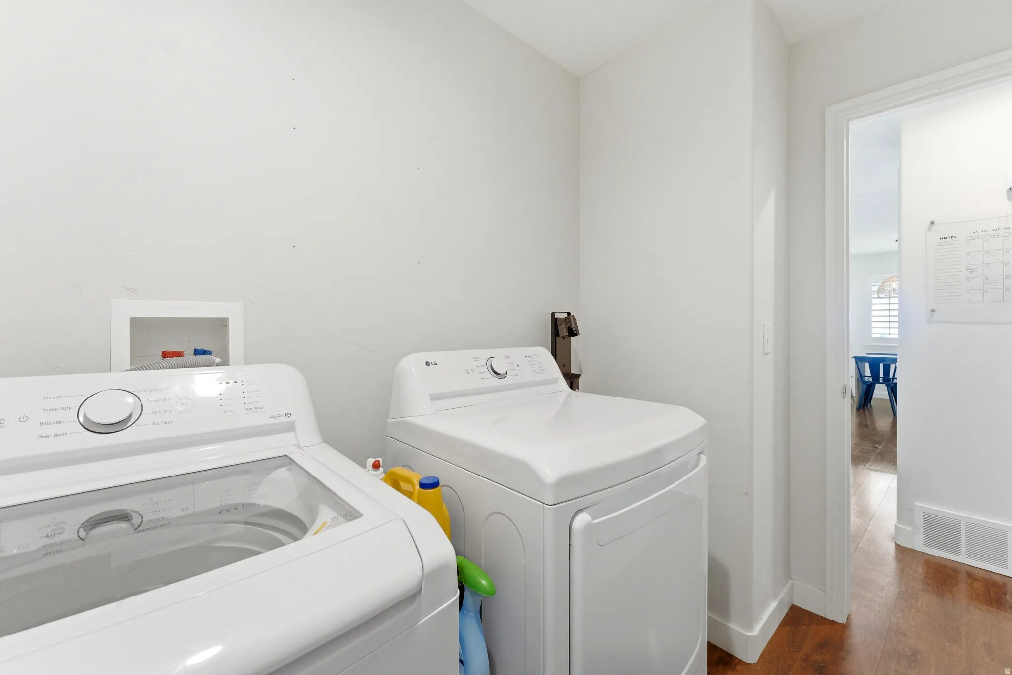 Dedicated laundry area featuring white walls and wood-finish flooring