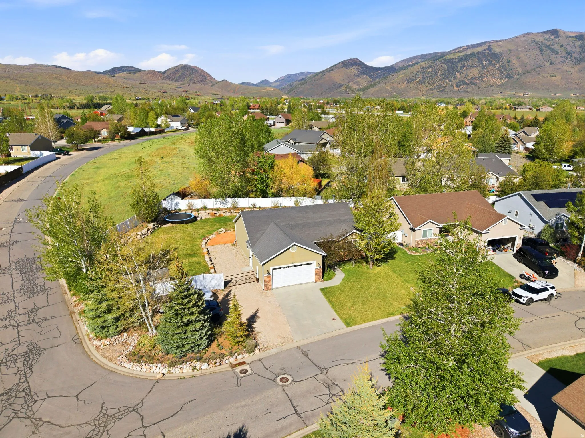 Ranch-style residence featuring a prominent garage, a paved driveway, and established landscaping